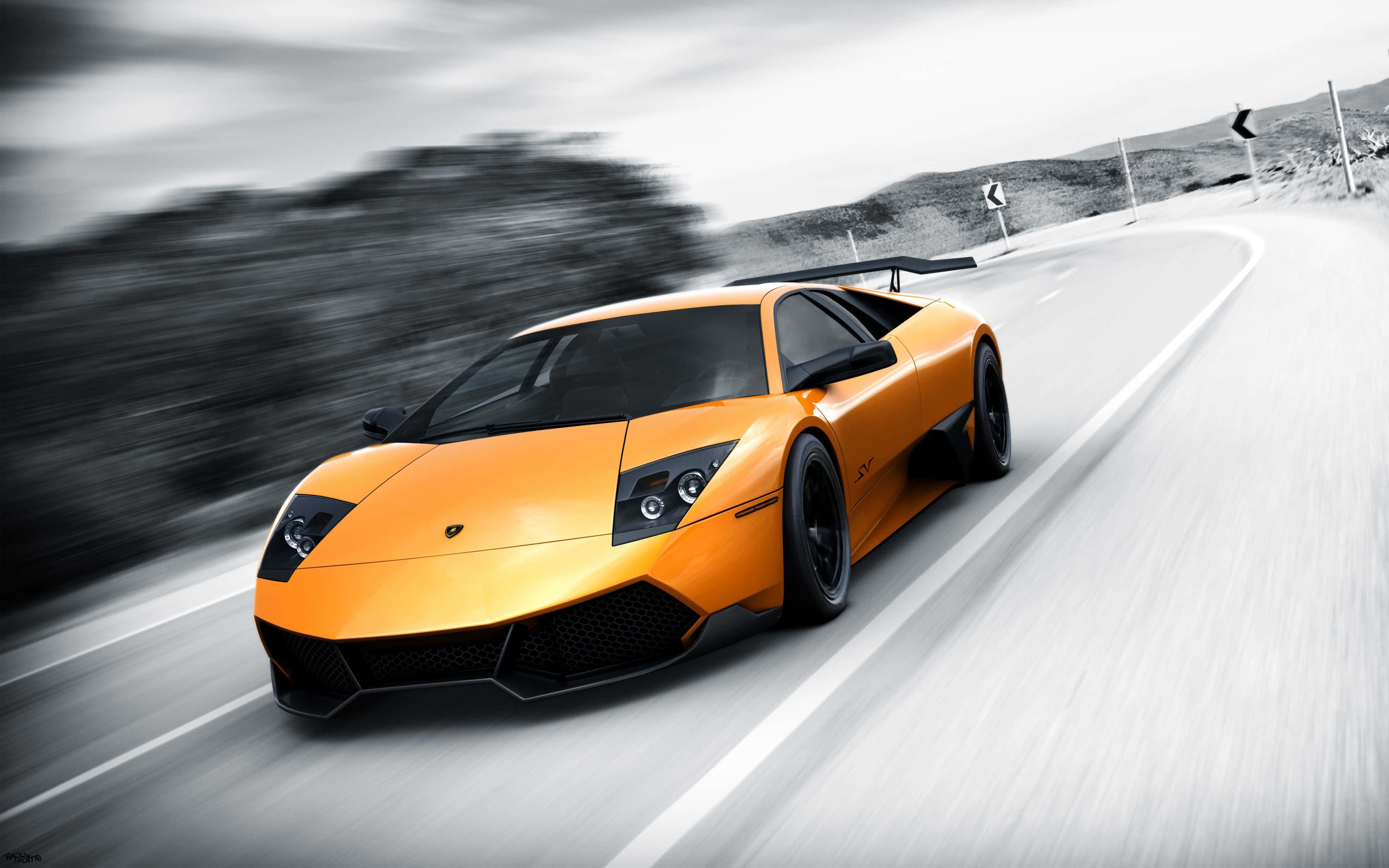 Lamborghini Murciélago 桌布 壁紙 — 一輛充滿活力的橙色林寶堅尼Reventon在蜿蜒的山路上飛馳，動態模糊效果強調其速度。