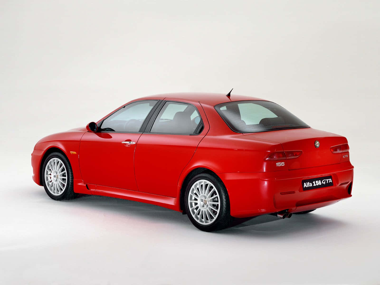 Alfa Romeo 156 桌布 壁紙 — 一輛充滿活力的紅色Alfa 156 GTA轎車，以四分之三後視圖展示在潔白的攝影棚背景前。