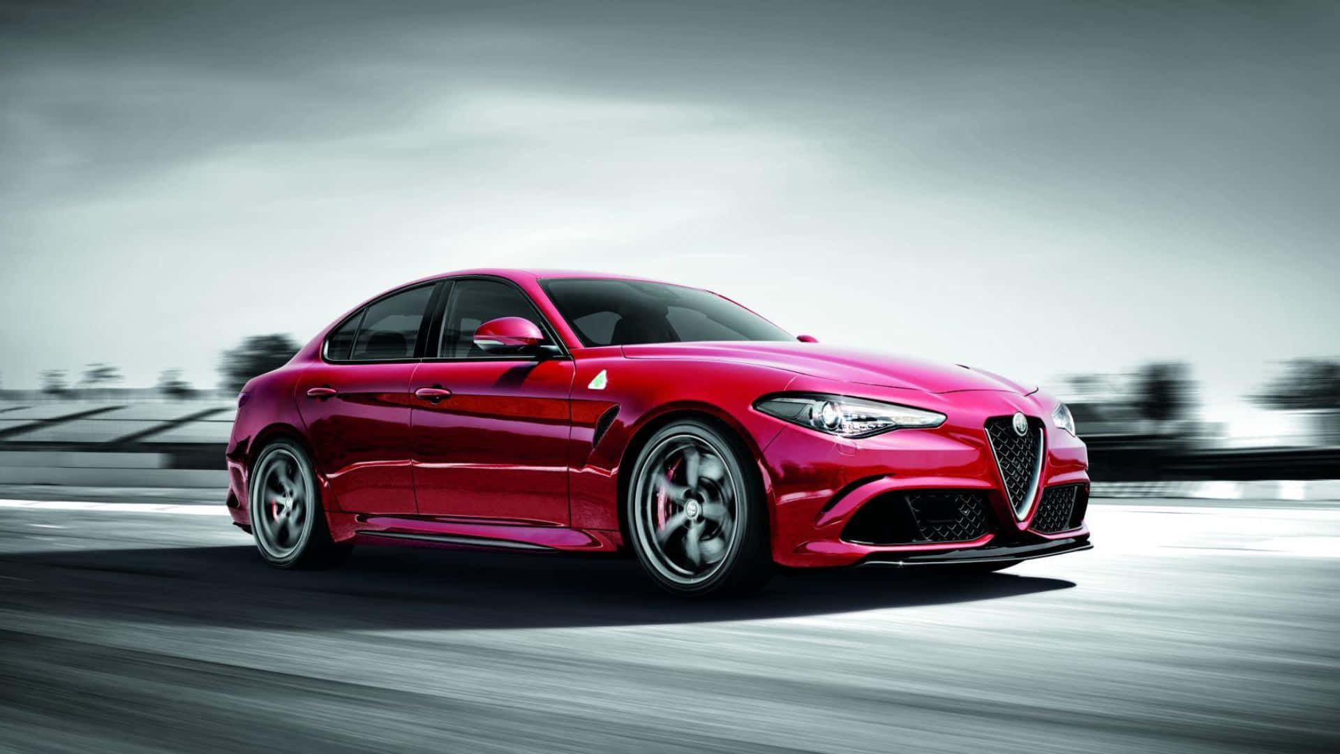 Alfa Romeo Giulia 桌布 壁紙 — 一輛充滿活力的紅色愛快羅密歐Giulia Quadrifoglio在陰天下的模糊賽道上疾馳。