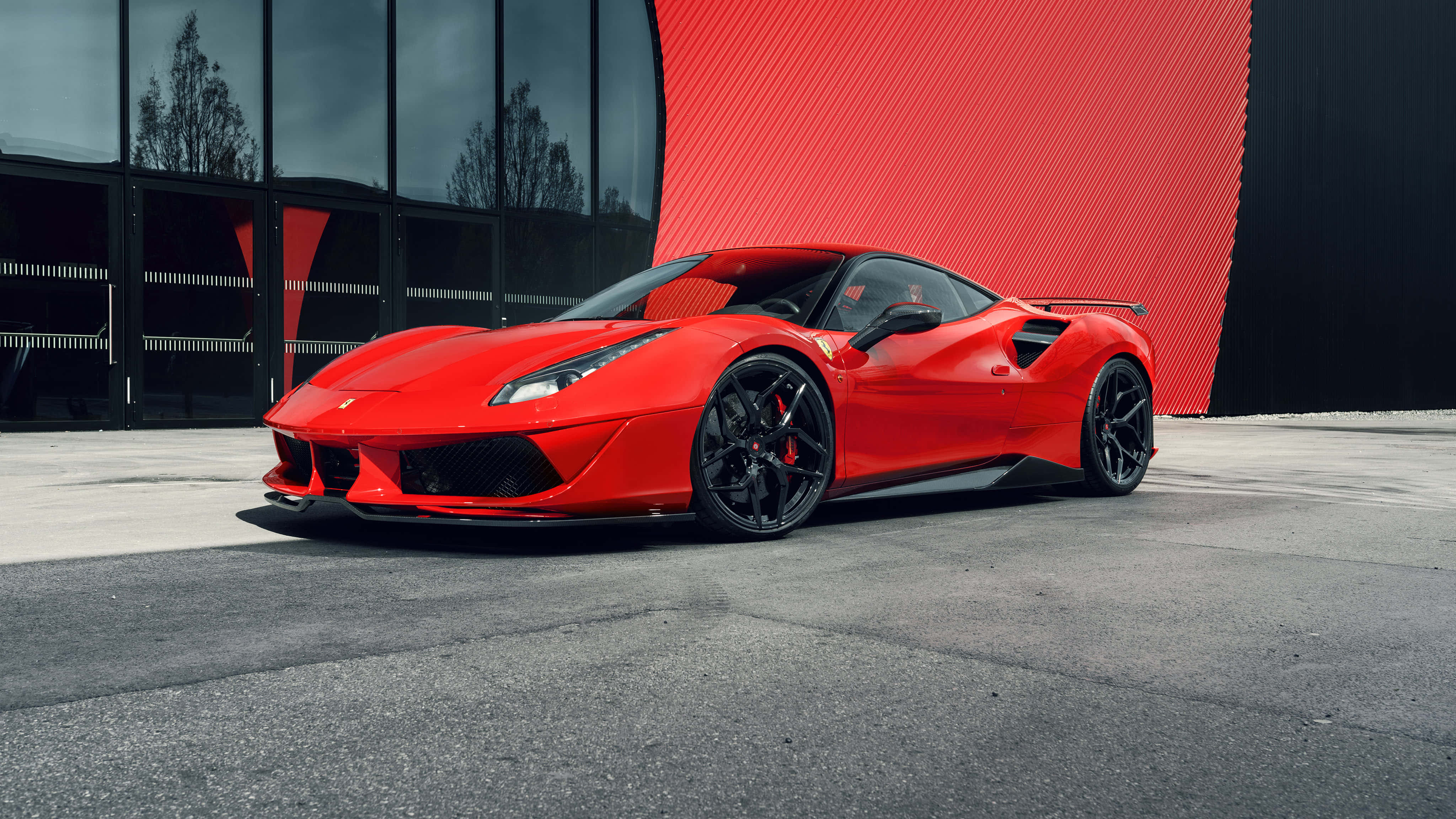 Ferrari 488 Spider 桌布 壁紙 — 一輛充滿活力的紅色法拉利跑車，帶有黑色裝飾，停在混凝土上，前面是一座現代建築，有玻璃窗和紅色紋理牆。