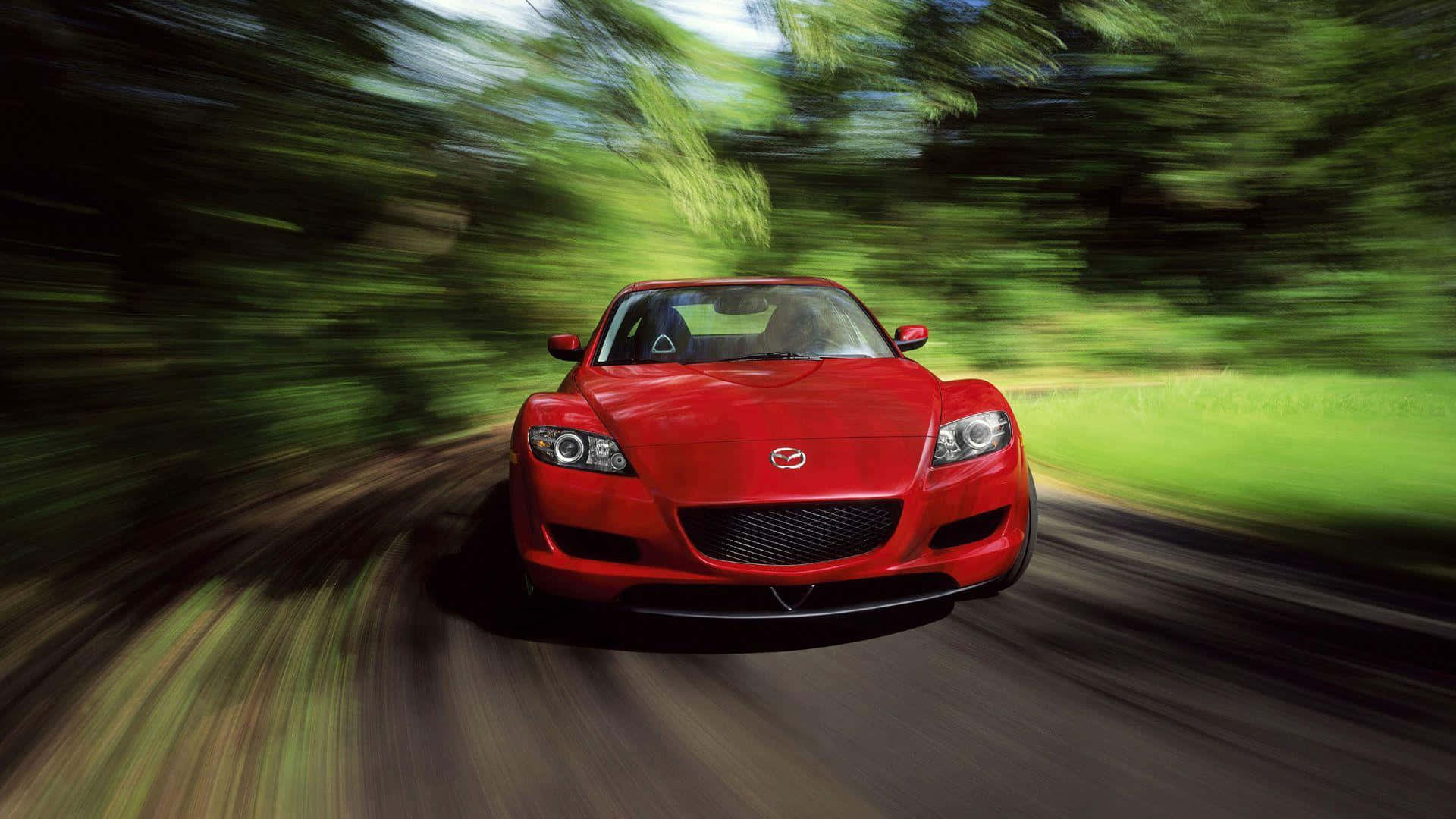 Mazda Rx-8 桌布 壁紙 — 一輛充滿活力的紅色跑車在森林環繞的道路上高速行駛，動態模糊效果強調了它的速度。