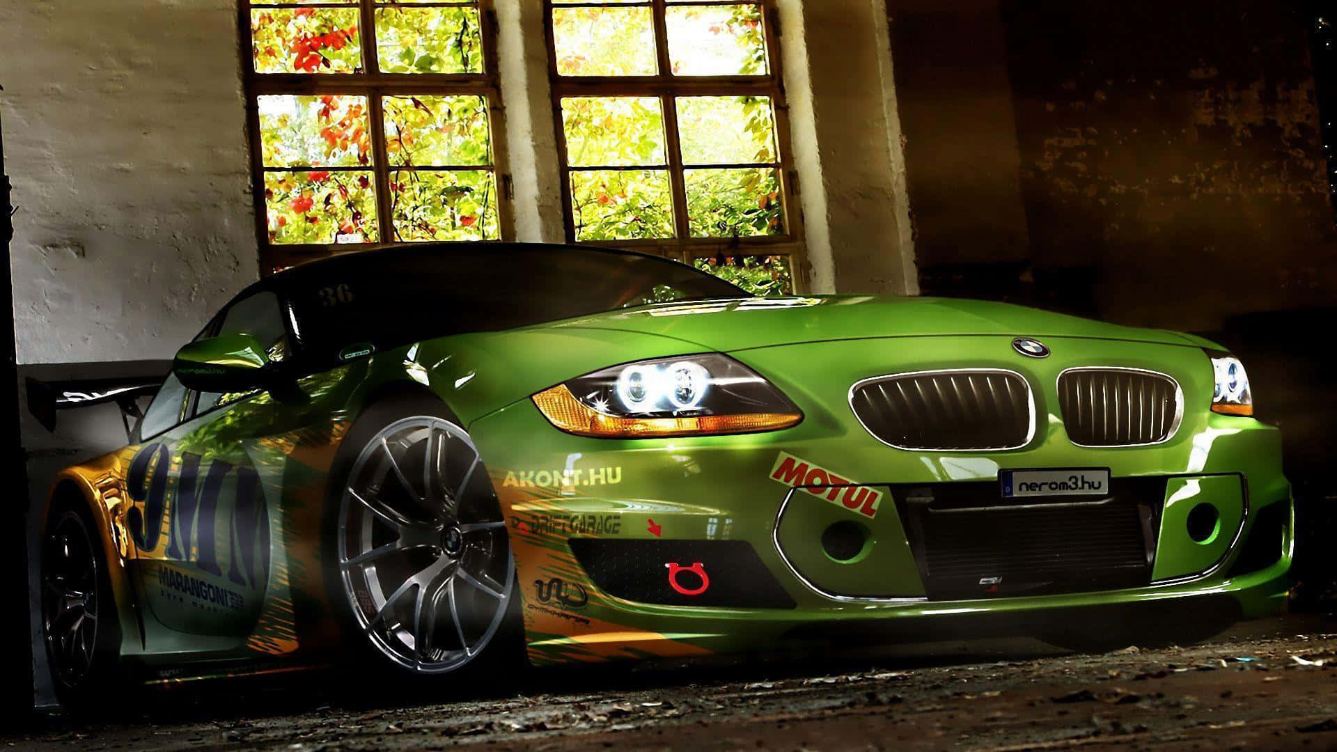 Modified Car 桌布 壁紙 — 一輛充滿活力的綠色BMW賽車，帶有贊助商貼紙，停放在一個質樸的倉庫內，金色陽光透過高窗照射進來，窗外可見秋葉。
