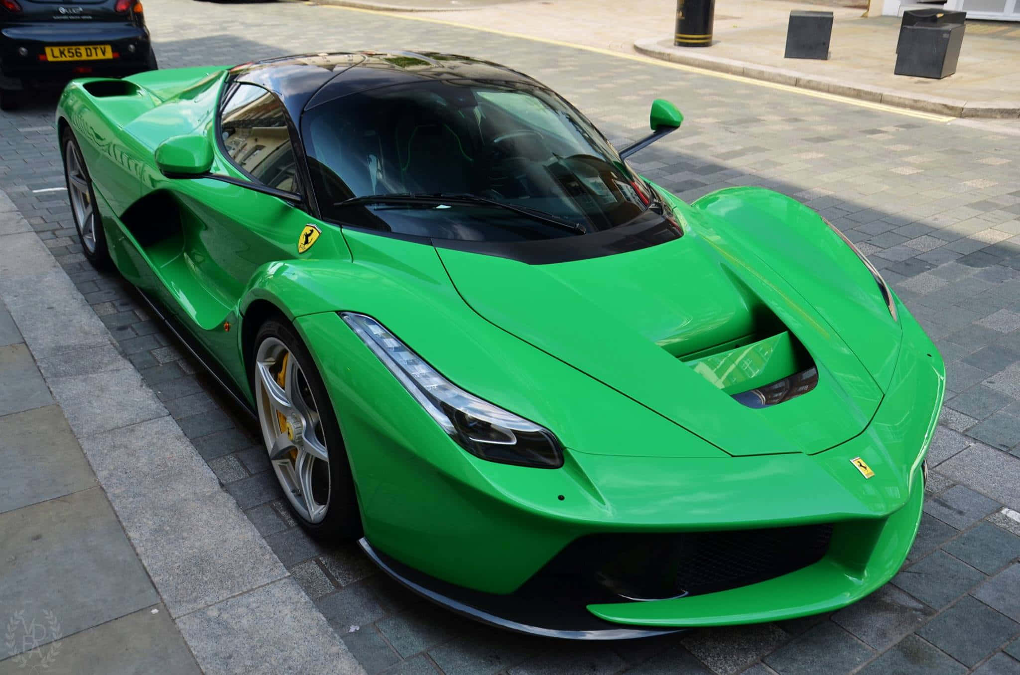Ferrari Laferrari 桌布 壁紙 — 一輛充滿活力的綠色法拉利LaFerrari停放在鋪砌的城市街道上，陽光在其時尚的空氣動力學車身上反射。