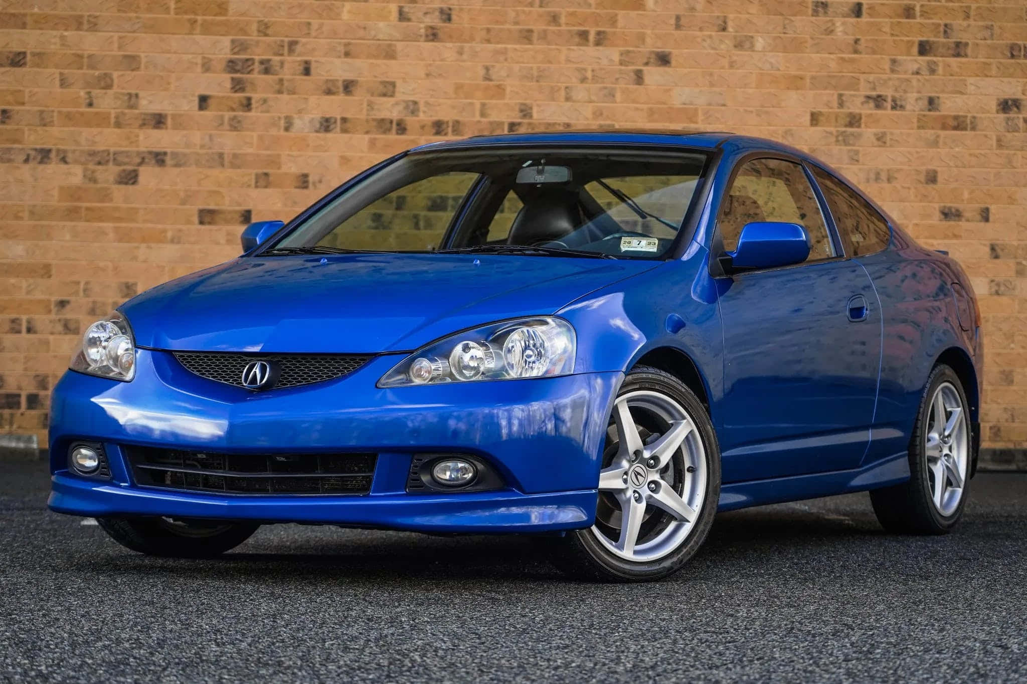 Acura Rsx 桌布 壁紙 — 一輛充滿活力的藍色Acura TSX雙門轎跑車在日光下閃耀，背景是紋理磚牆。
