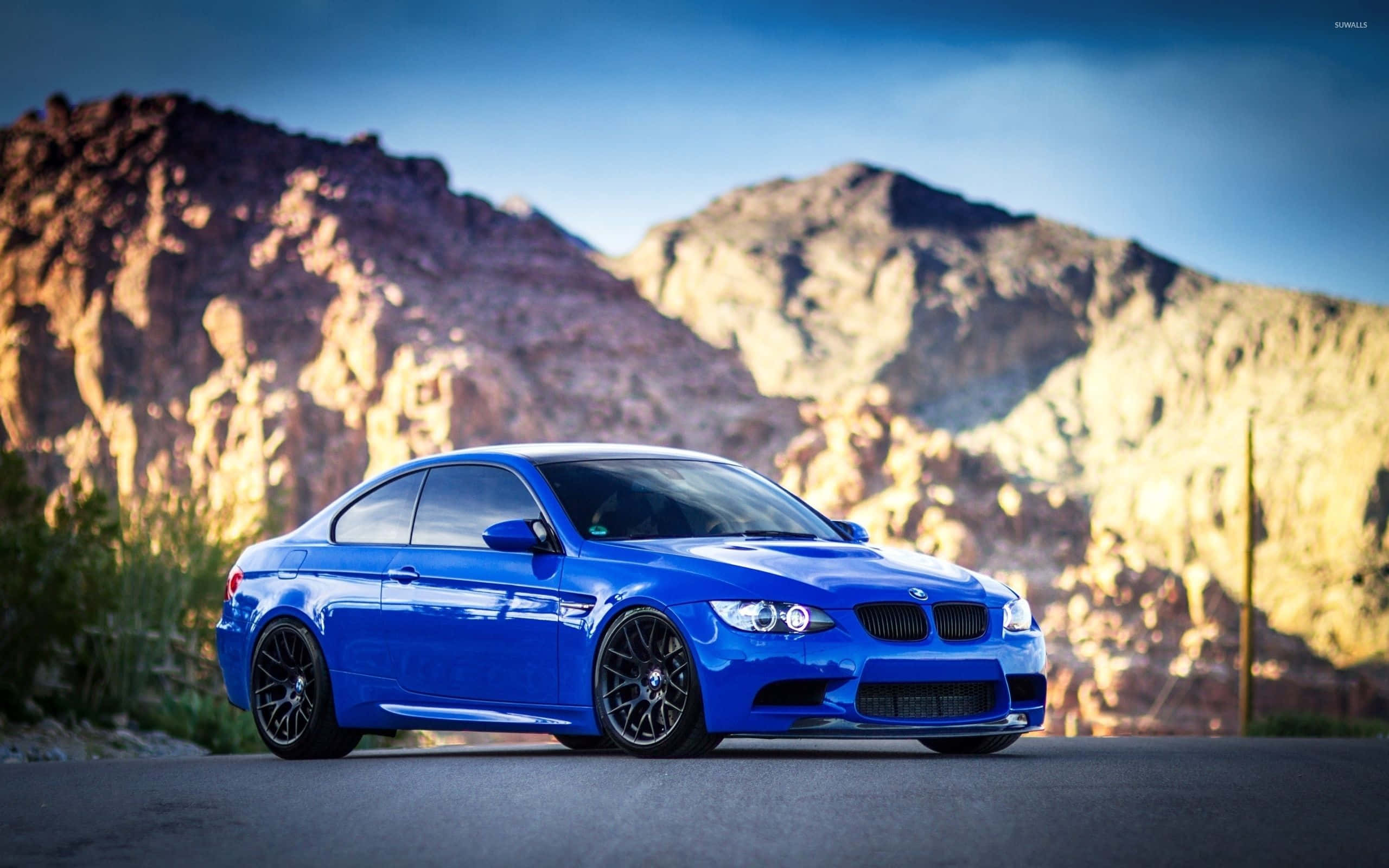 Bmw 4 Series 桌布 壁紙 — 一輛充滿活力的藍色BMW M3雙門轎跑車在金色陽光下閃耀，背景是崎嶇的沙漠山脈。