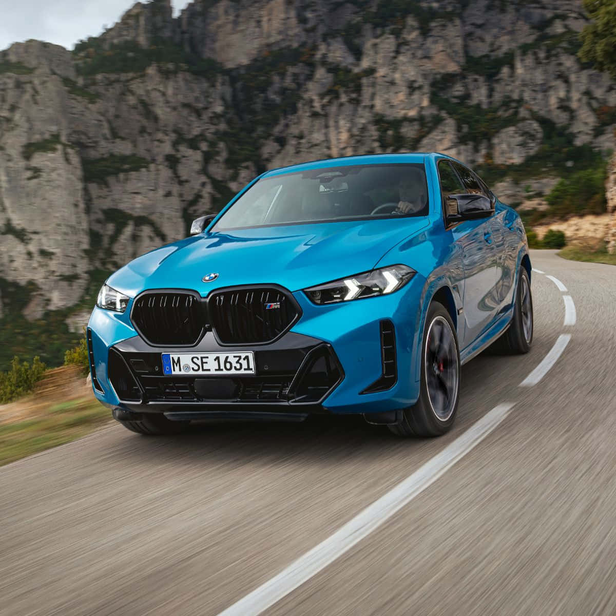Bmw X5 桌布 壁紙 — 一輛充滿活力的藍色BMW M8 Coupe在蜿蜒的山路上疾馳，背景是崎嶇的懸崖。
