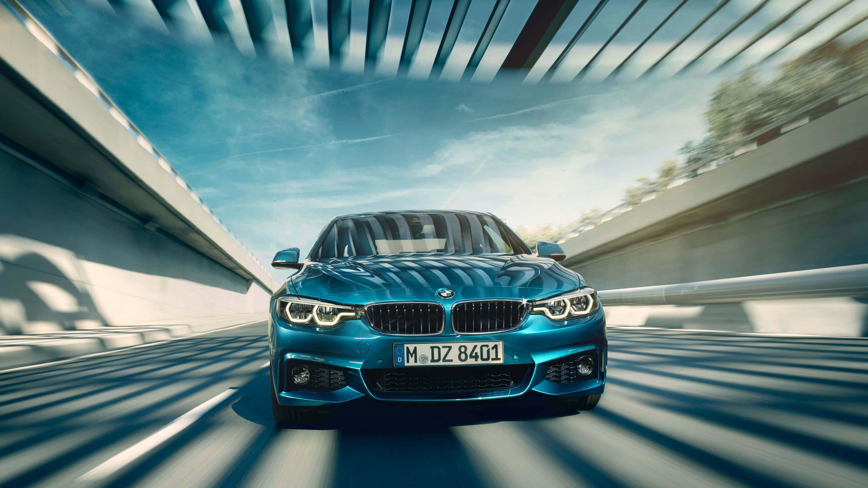 Bmw 4 Series 桌布 壁紙 — 一輛充滿活力的藍色BMW跑車在現代混凝土橋樑上疾馳，背景是明亮的藍天，帶有動態模糊條紋。