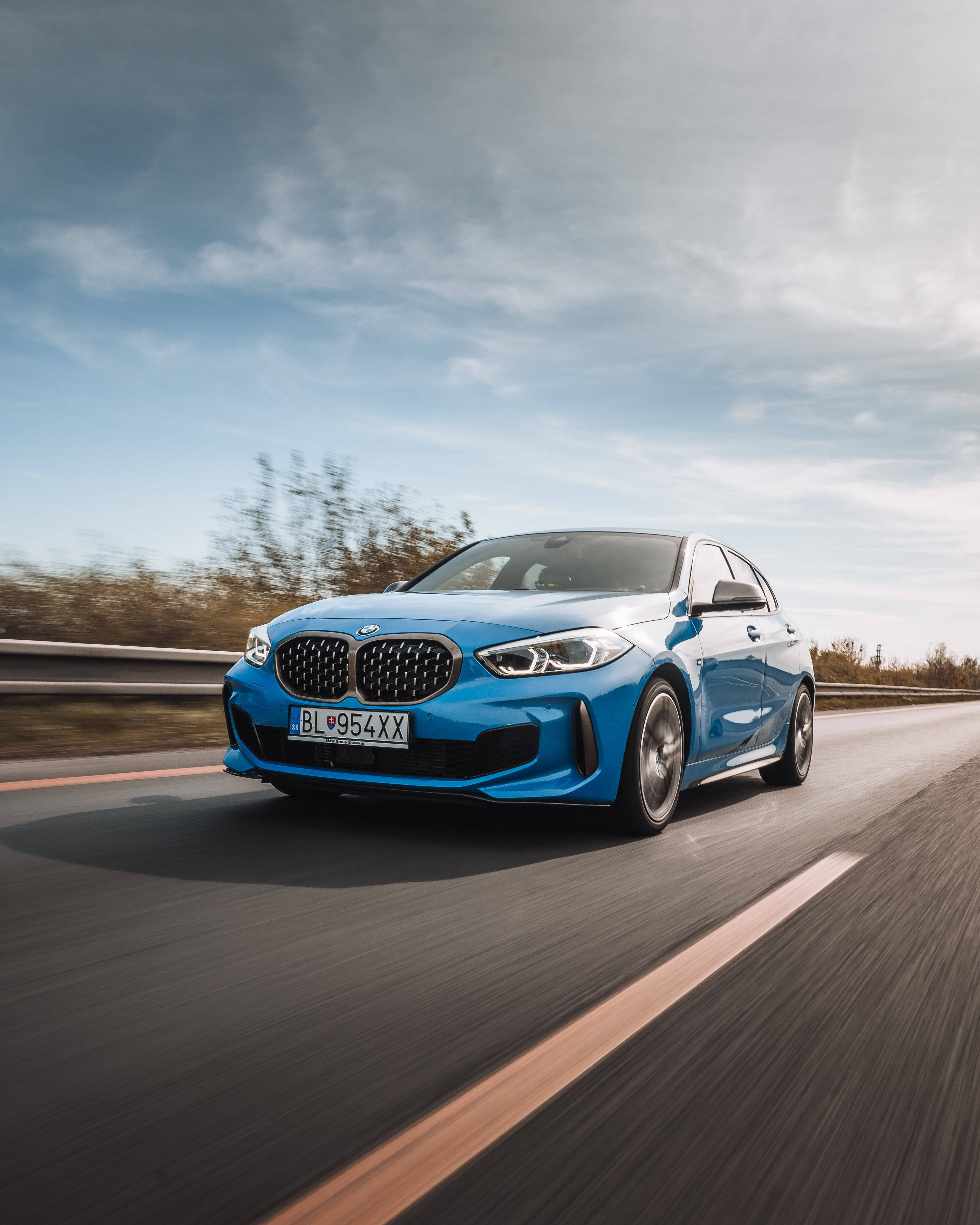 speeding car 桌布 壁紙 — 一輛充滿活力的藍色BMW跑車在陰天的高速公路上疾馳，路邊樹木模糊。