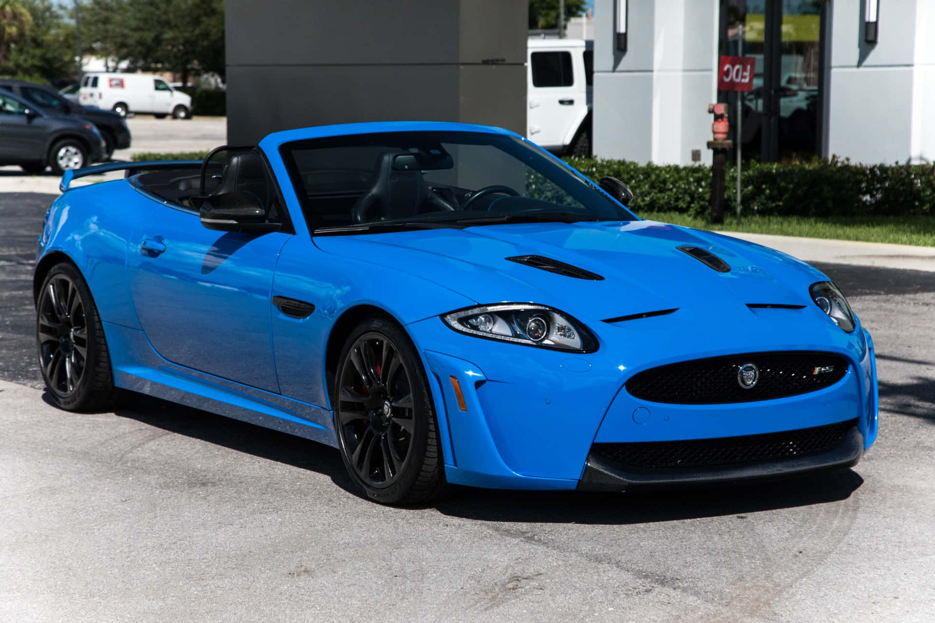 Jaguar Xkr 桌布 壁紙 — 一輛充滿活力的藍色Jaguar XKR開篷車停在瀝青路上，配備黑色輪圈和時尚的空氣動力學設計。