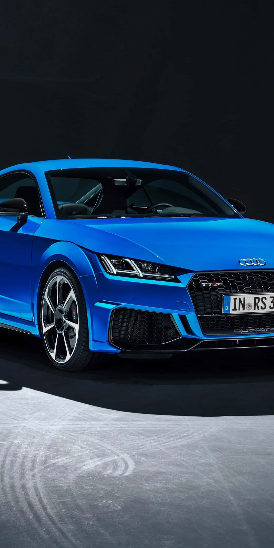 Audi Tt 桌布 壁紙 — 一輛充滿活力的藍色奧迪TT RS跑車在攝影棚燈光下，在帶有輪胎痕的混凝土表面上閃閃發光。