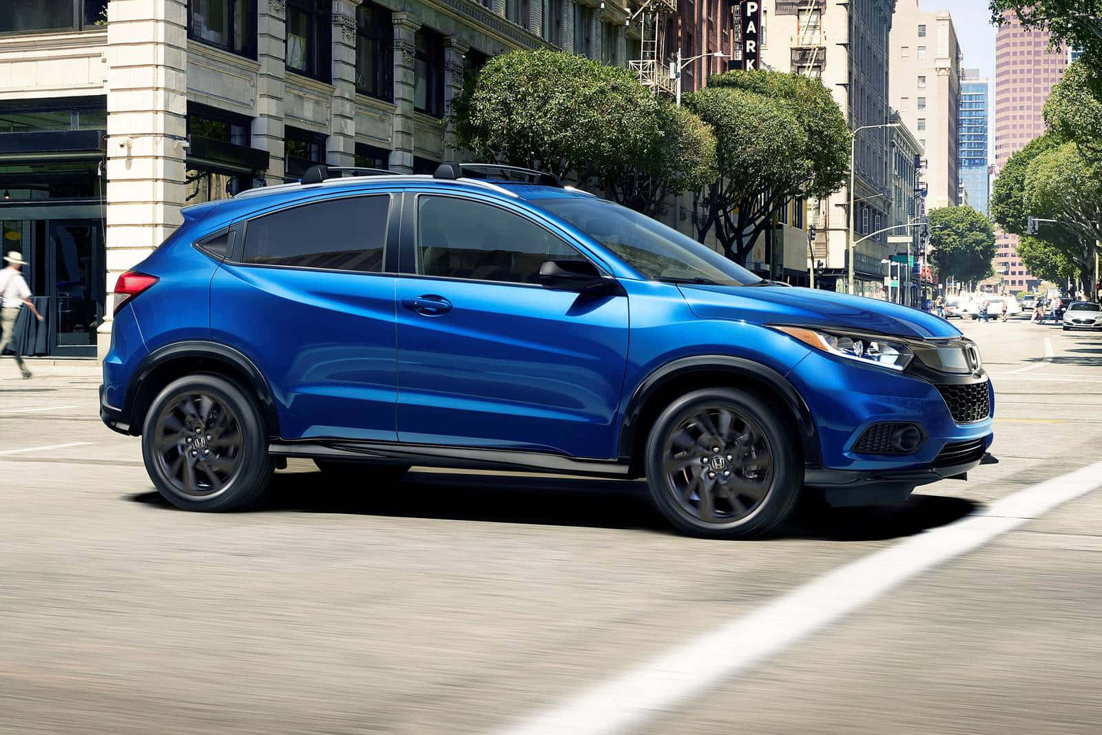 Honda Hr-v 桌布 壁紙 — 一輛充滿活力的藍色本田 HR-V SUV 在陽光明媚的城市街道上行駛，道路上有動態模糊效果。