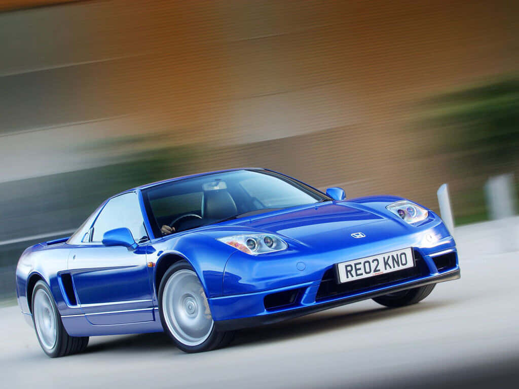 Honda Nsx 桌布 壁紙 — 一輛充滿活力的藍色本田NSX跑車在模糊的道路上疾馳，動態模糊強調了其動態運動。