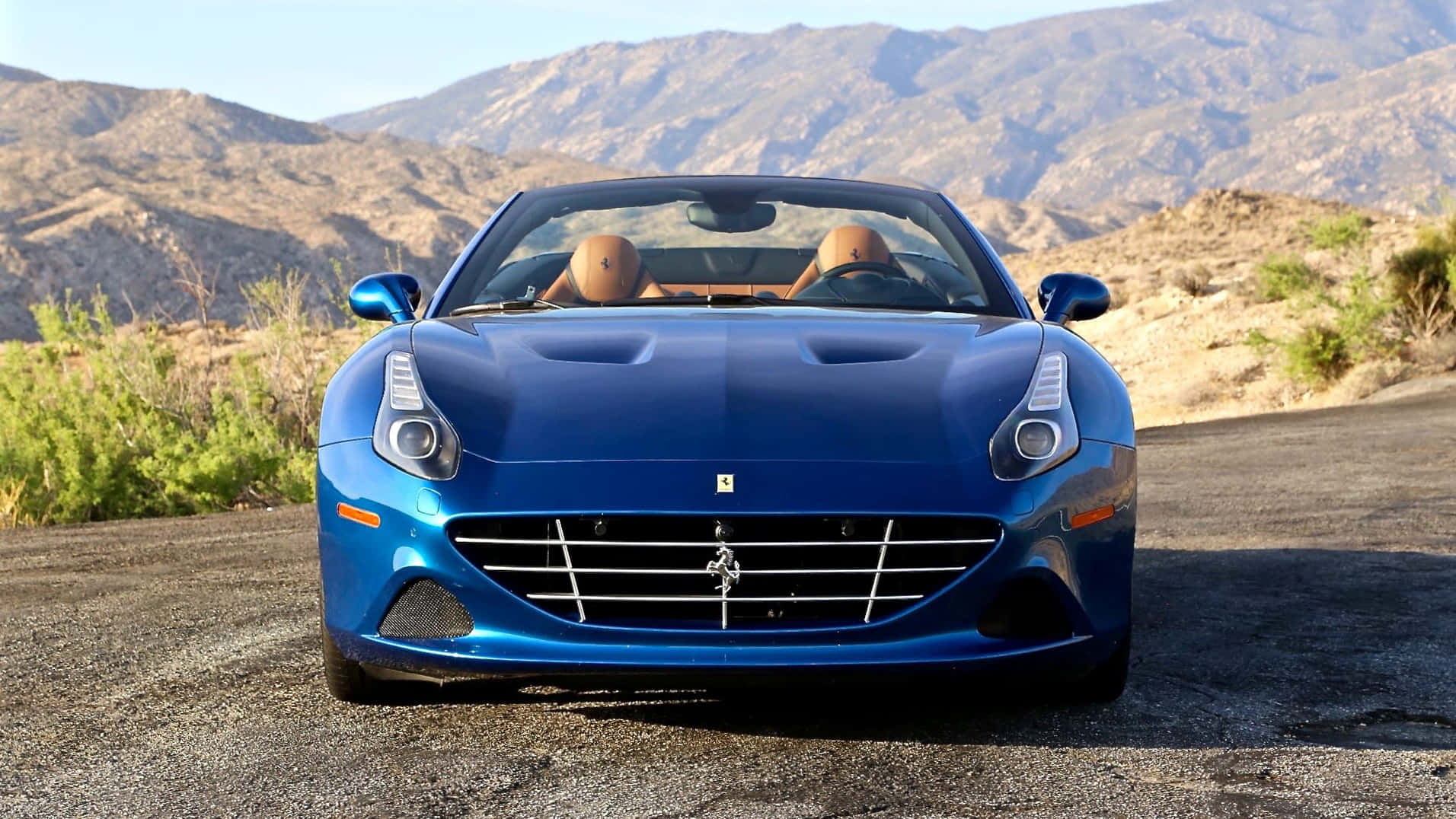 Ferrari California T 桌布 壁紙 — 一輛充滿活力的藍色法拉利加利福尼亞開篷跑車停在沙漠公路上，背景是崎嶇的山脈。