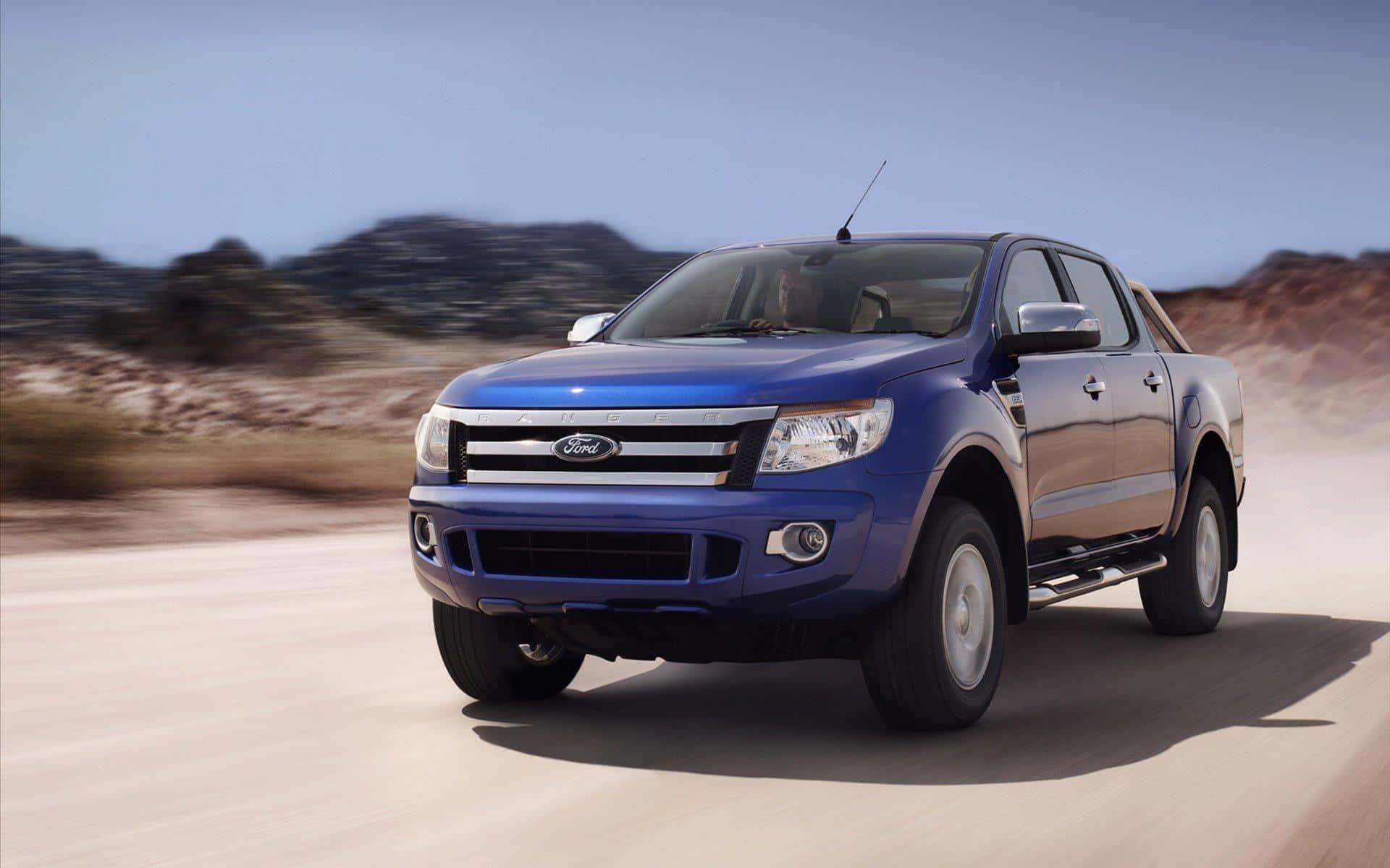 Ford Ranger 桌布 壁紙 — 一輛充滿活力的藍色福特皮卡在塵土飛揚的沙漠公路上疾馳，背景是模糊的岩石山丘。