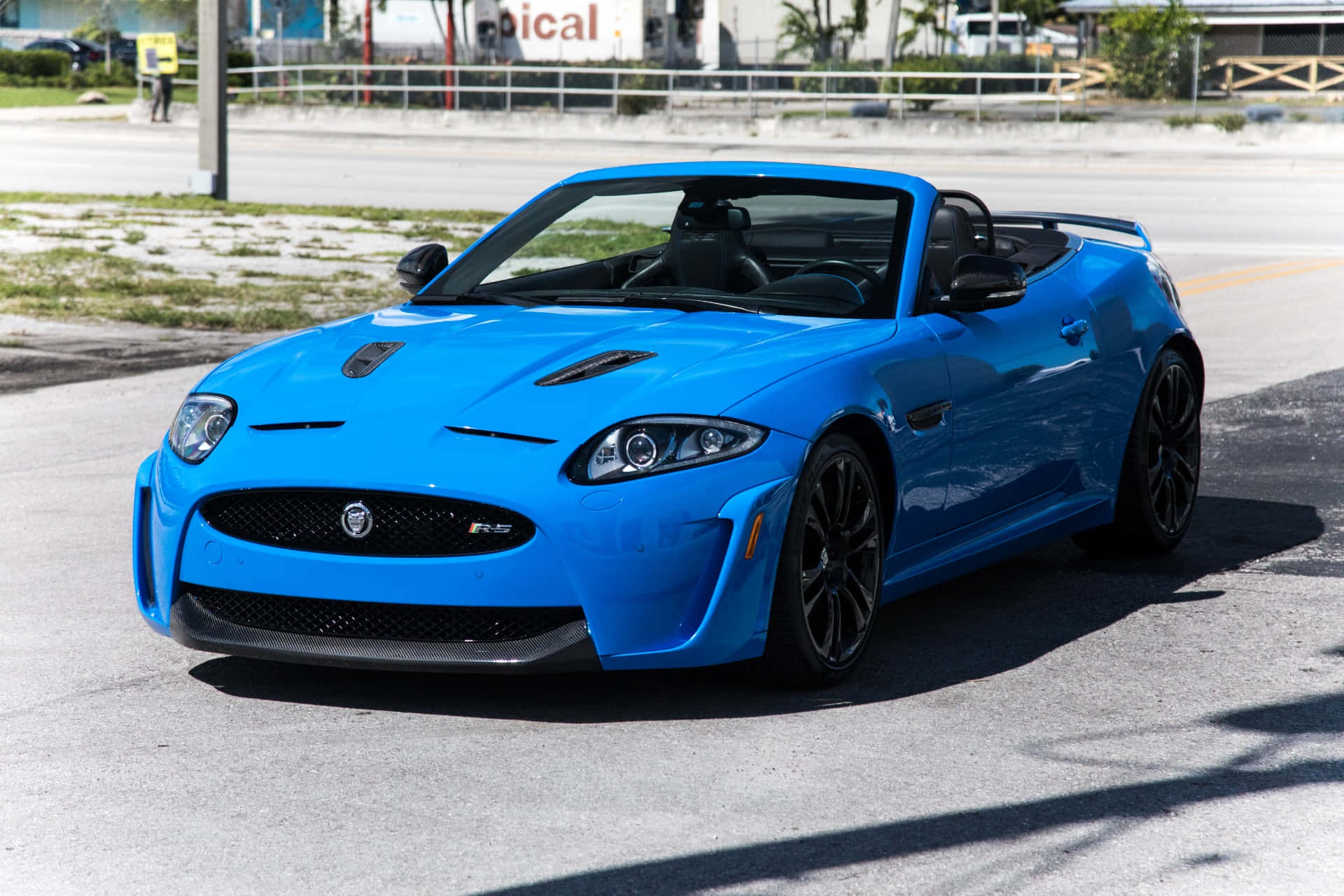Jaguar Xkr 桌布 壁紙 — 一輛充滿活力的藍色積架XKR開篷車停在瀝青路上，配備黑色車輪和時尚的空氣動力學設計。