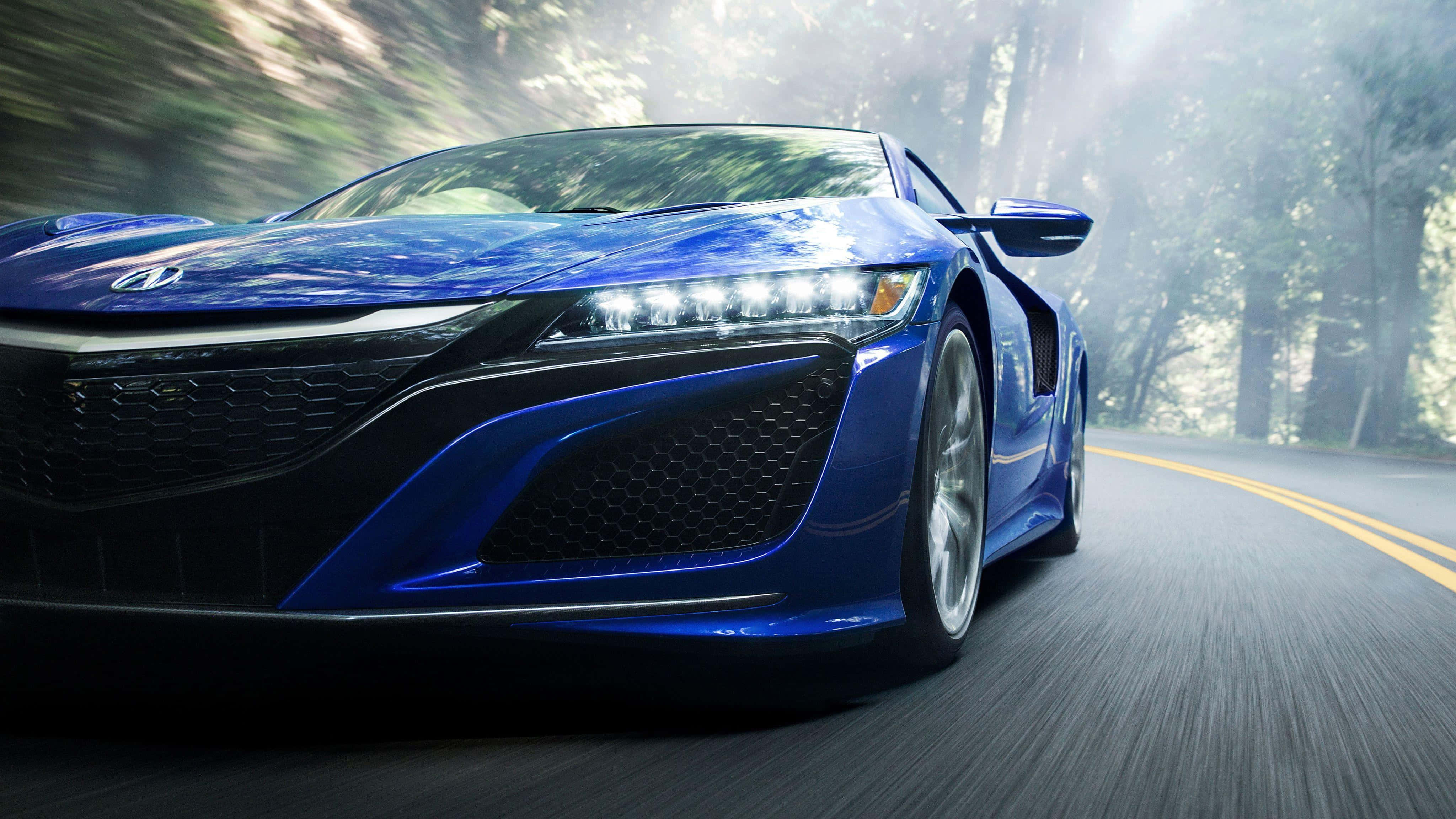 Acura Nsx 桌布 壁紙 — 一輛充滿活力的藍色跑車在樹木林立的道路上疾馳，帶有動態模糊效果，陽光穿過樹林灑落。
