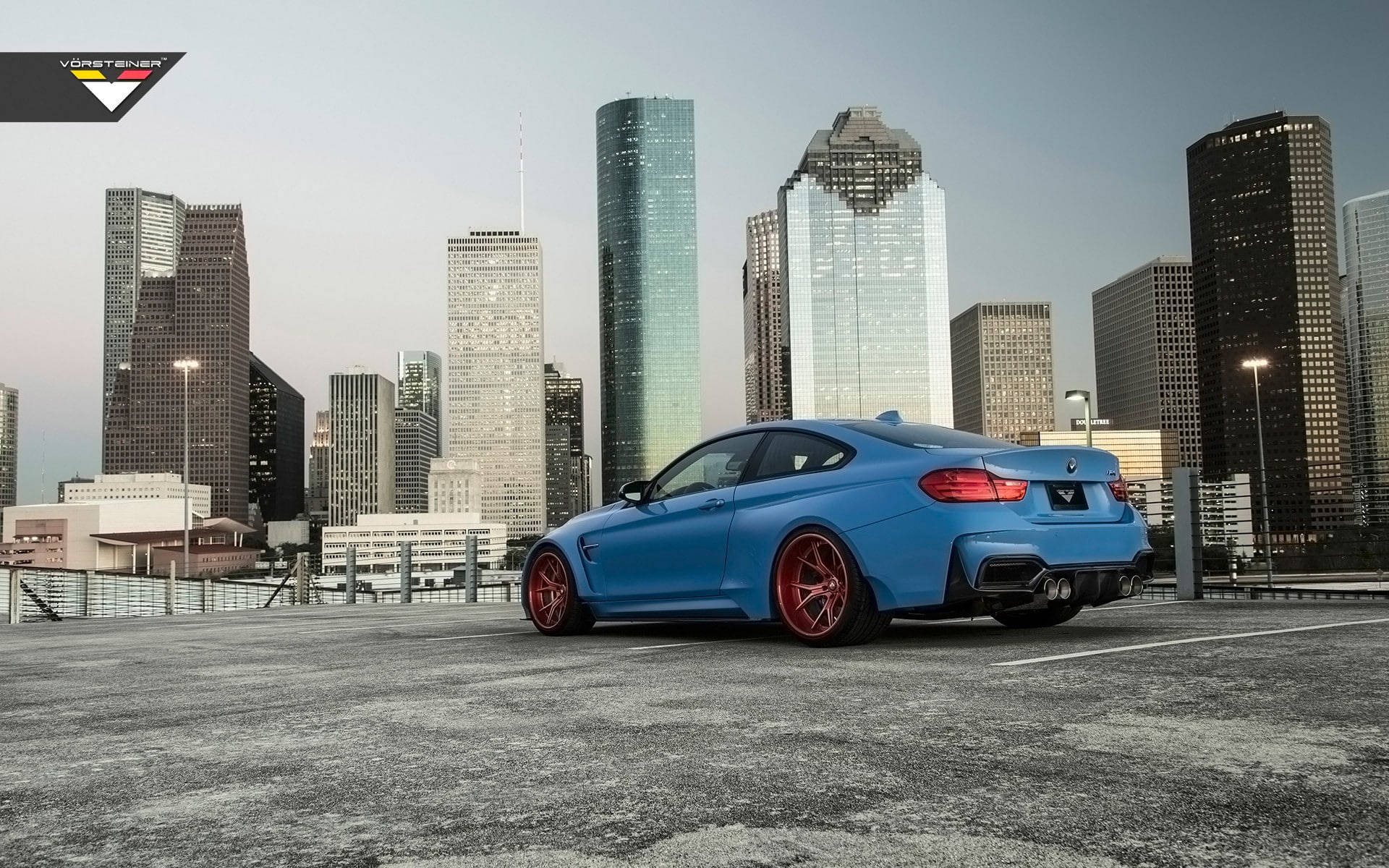 Sports Car 桌布 壁紙 — 一輛充滿活力的藍色跑車配紅色輪圈，停泊在可俯瞰現代城市天際線的屋頂上，正值黃昏時分。