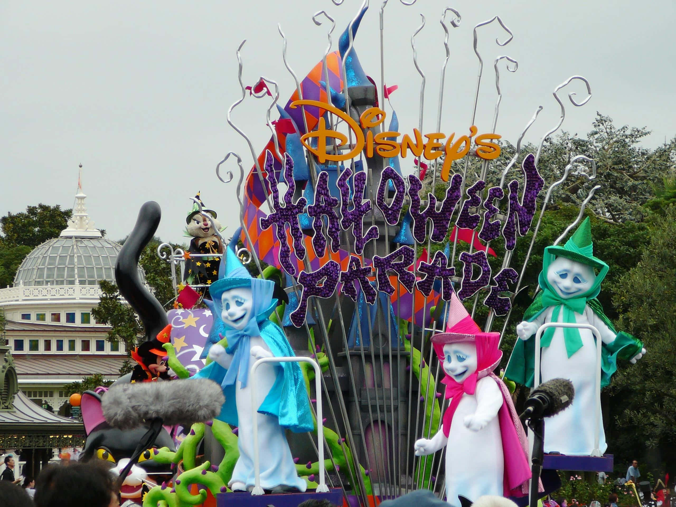 Halloween Parades 桌布 壁紙 — 一輛充滿活力的迪士尼萬聖節巡遊花車，以多雲的天空為背景，展示色彩繽紛的女巫角色和恐怖裝飾。