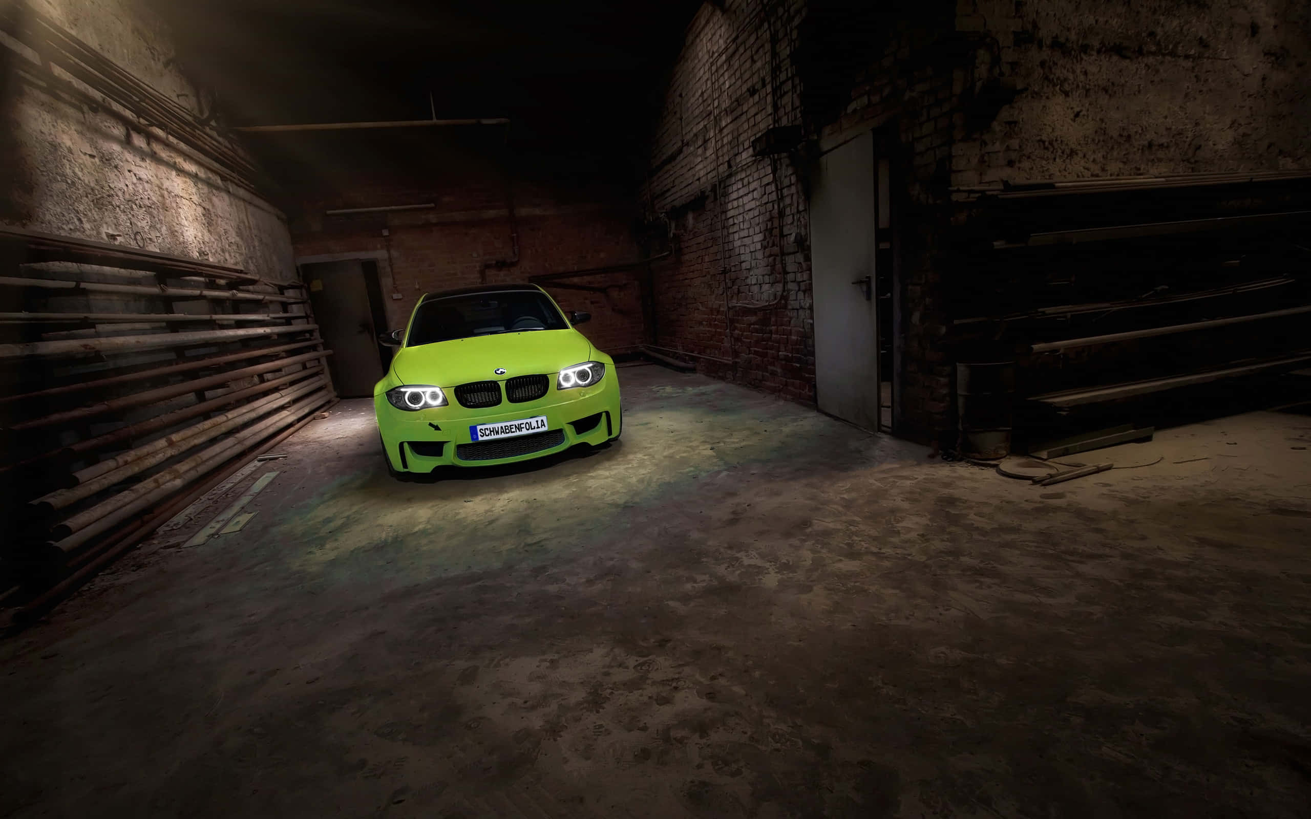 Bmw 1 Series 桌布 壁紙 — 一輛充滿活力的青檸綠色BMW M3跑車在昏暗、粗糙的工業倉庫中，於車頭燈下閃耀。