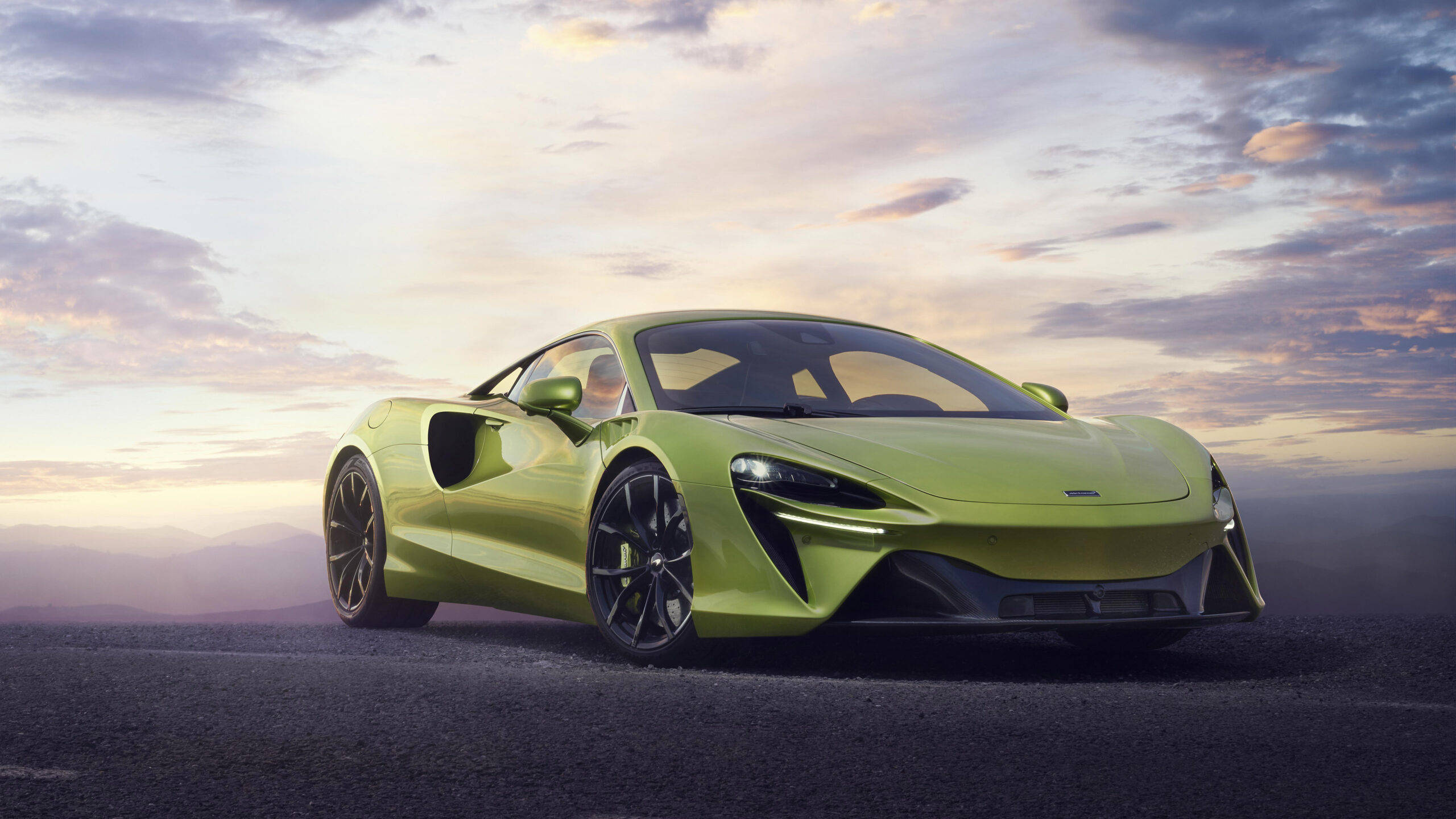 Sports Car 桌布 壁紙 — 一輛充滿活力的青檸綠色McLaren跑車在柔和嘅日落天空下閃閃發光，背景係遠處嘅山脈。