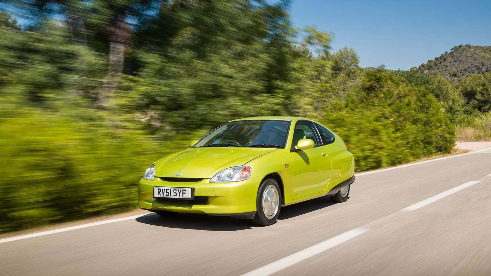 Honda Insight 桌布 壁紙 — 一輛充滿活力的青檸綠色本田 Insight 在陽光明媚的鄉村道路上飛馳，兩旁茂密的綠樹模糊掠過。