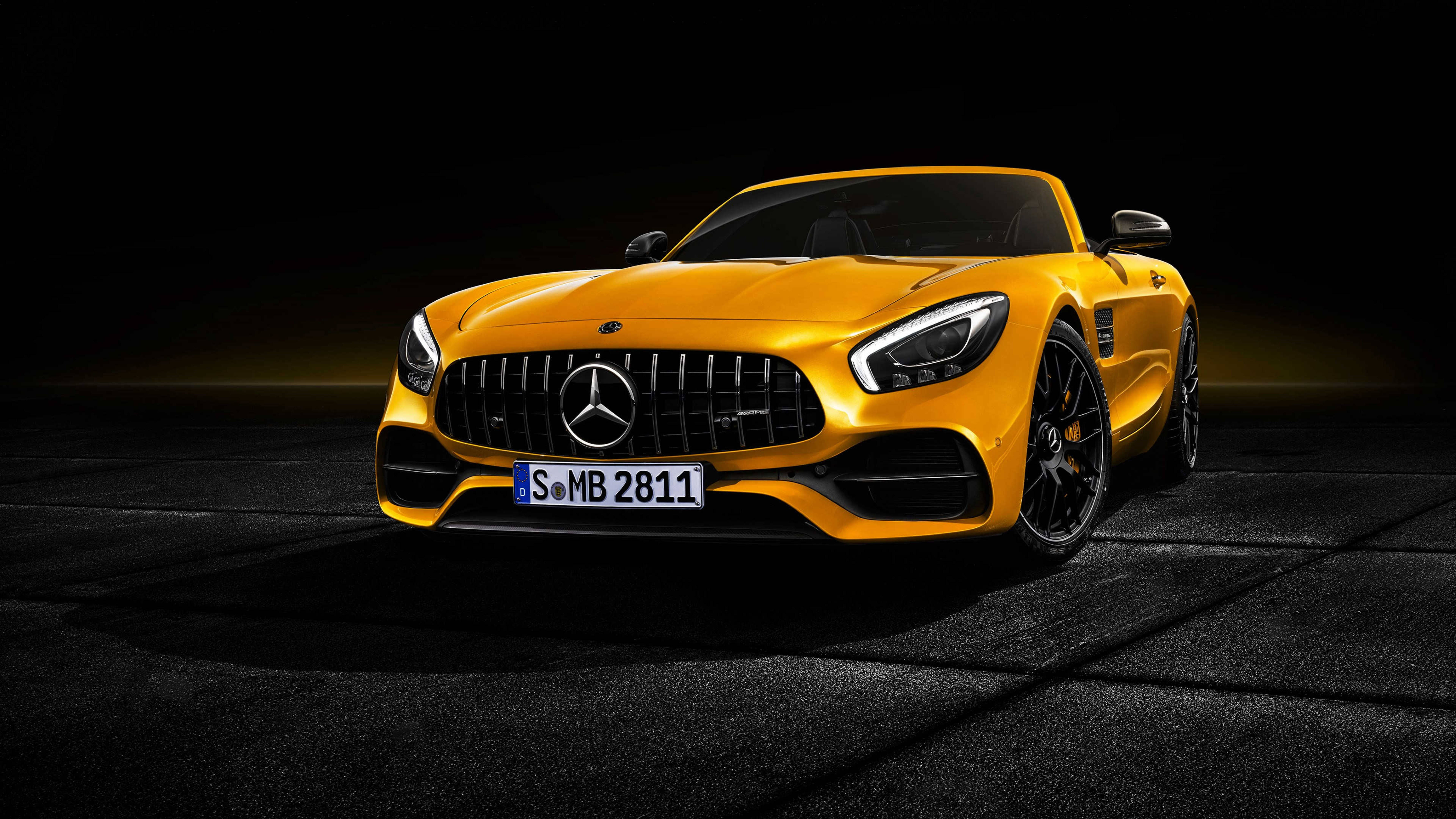 HD mercedes 桌布 壁紙 — 一輛充滿活力的黃色 Mercedes-AMG GT Roadster 在戲劇性燈光下，在深色工作室地板上閃閃發光。