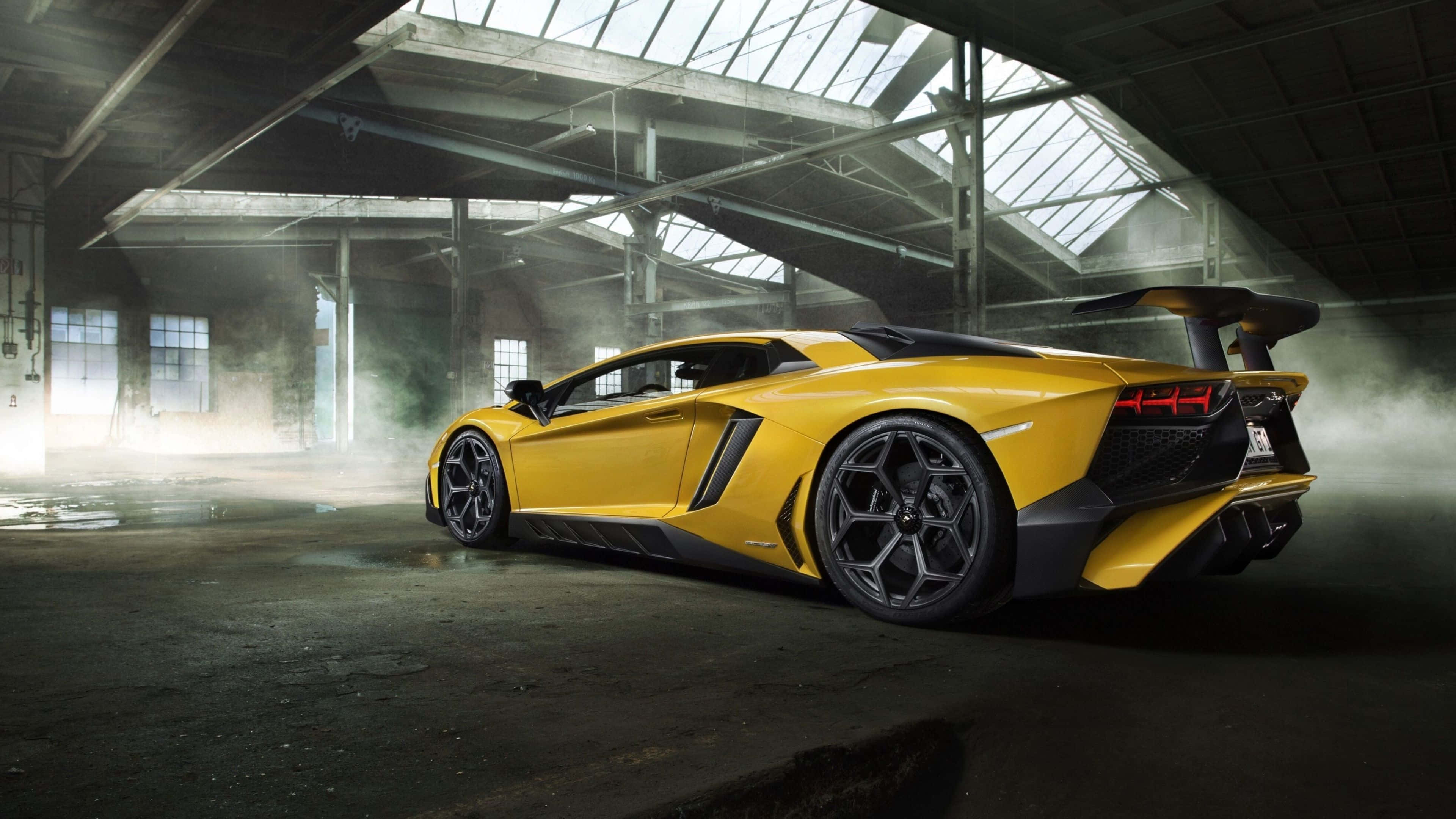 林寶堅尼 4K 桌布 壁紙 — 一輛充滿活力的黃色林寶堅尼 Aventador SVJ 在工業天窗下，於煙霧瀰漫的廢棄倉庫中閃閃發光。