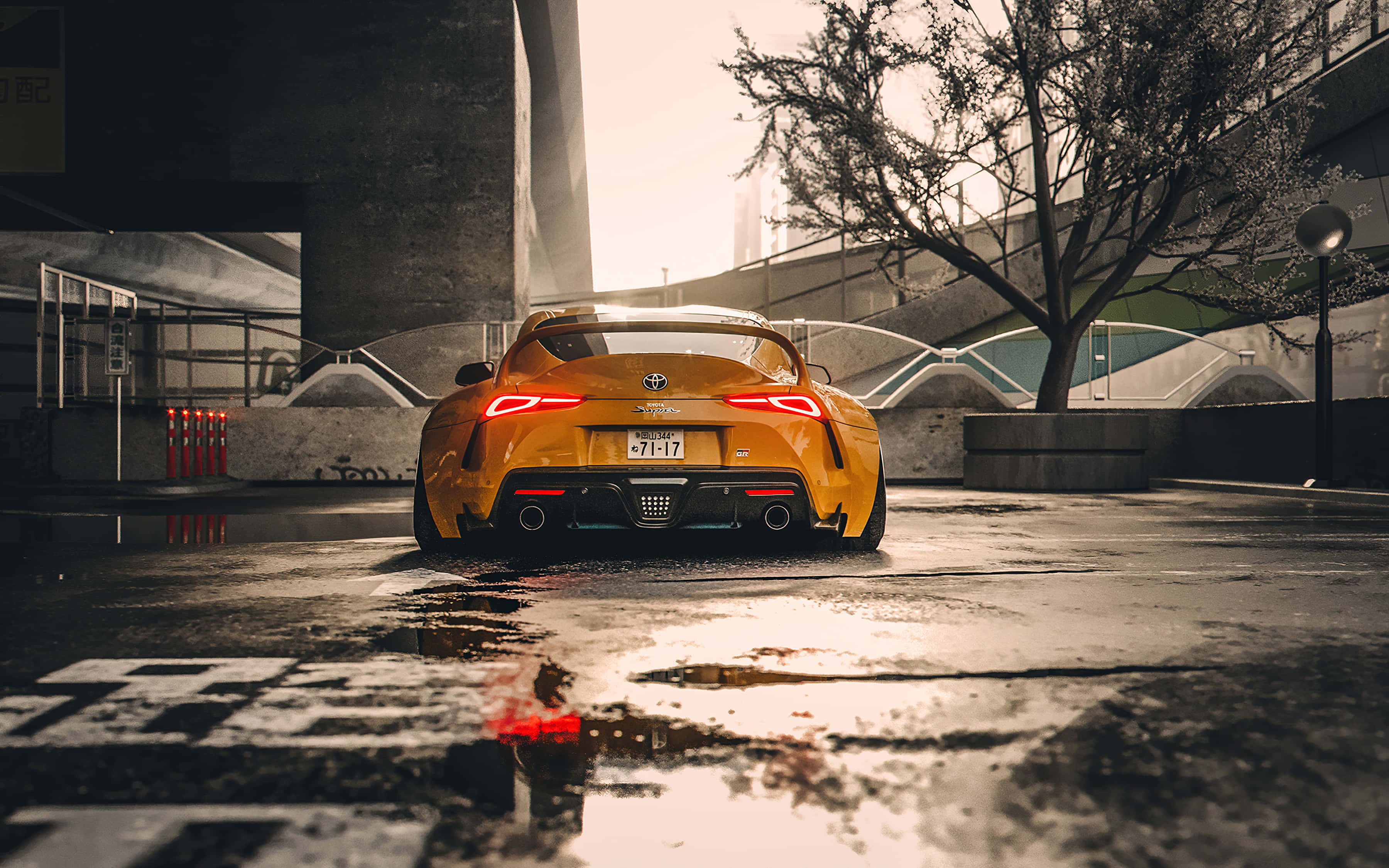 Supra 桌布 壁紙 — 一輛充滿活力的黃色跑車，帶有發光的紅色尾燈，停放在潮濕的城市街道上，反射著日出的柔和光芒。