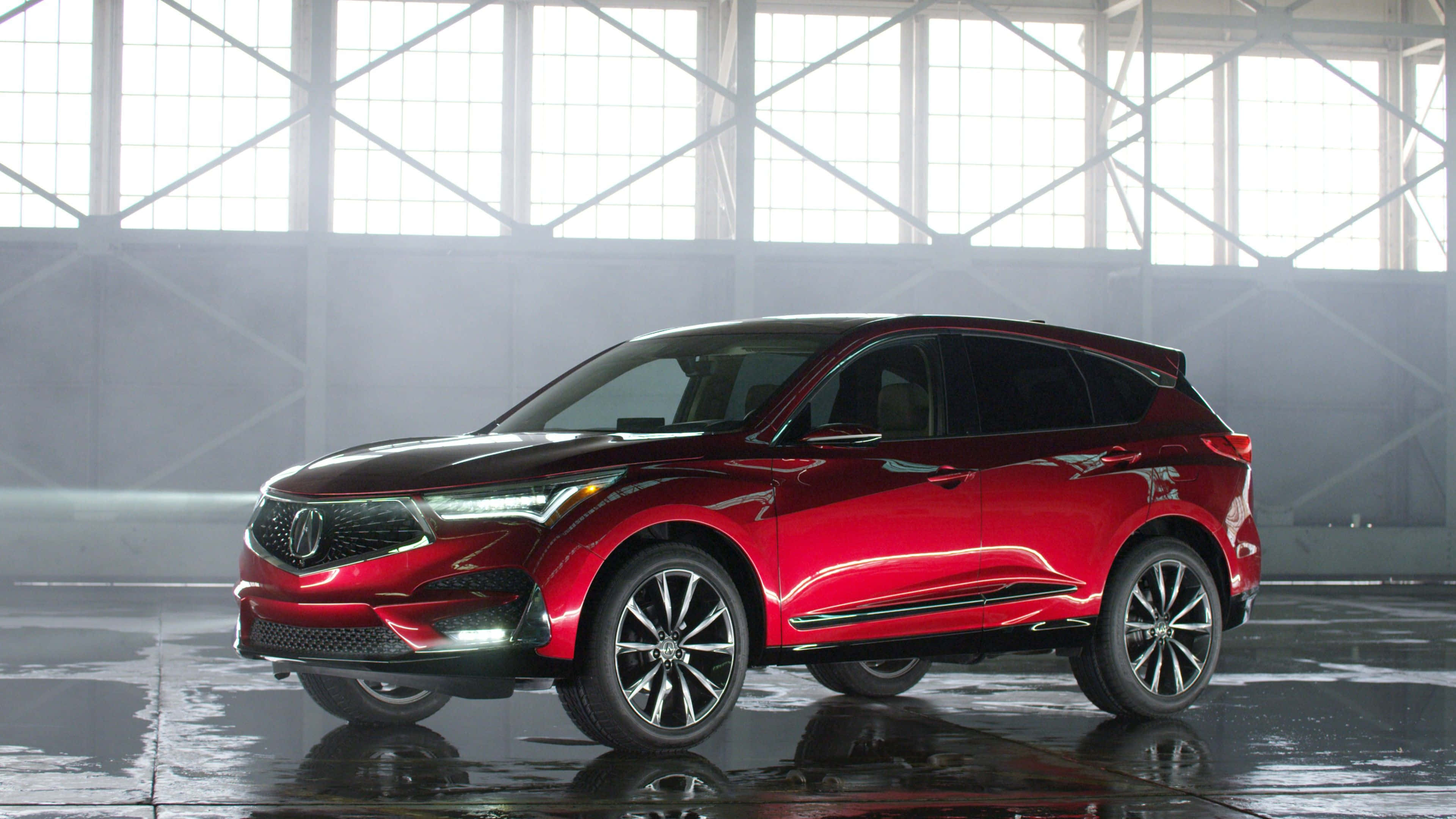 Acura Rdx 桌布 壁紙 — 一輛光亮的紅色SUV在明亮的工業窗戶下，於寬敞機庫的濕滑反光地板上閃耀。