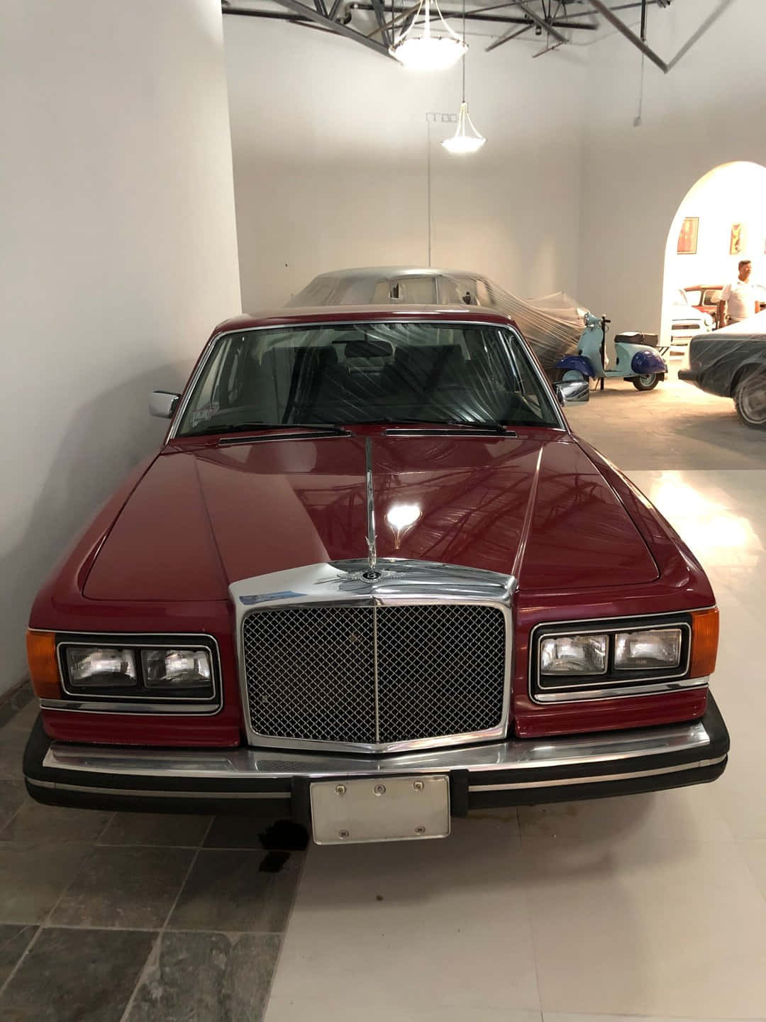 Bentley Eight 桌布 壁紙 — 一輛光亮的紅色梅賽德斯-奔馳轎車在明亮簡約的汽車陳列室中正面展示，地板舖有瓷磚，天花橫樑外露。