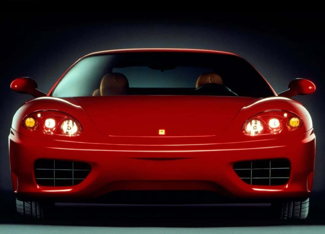 Ferrari 360 Modena 桌布 壁紙 — 一輛光亮的紅色法拉利跑車，車頭燈發光，擋風玻璃後可見兩名乘客。