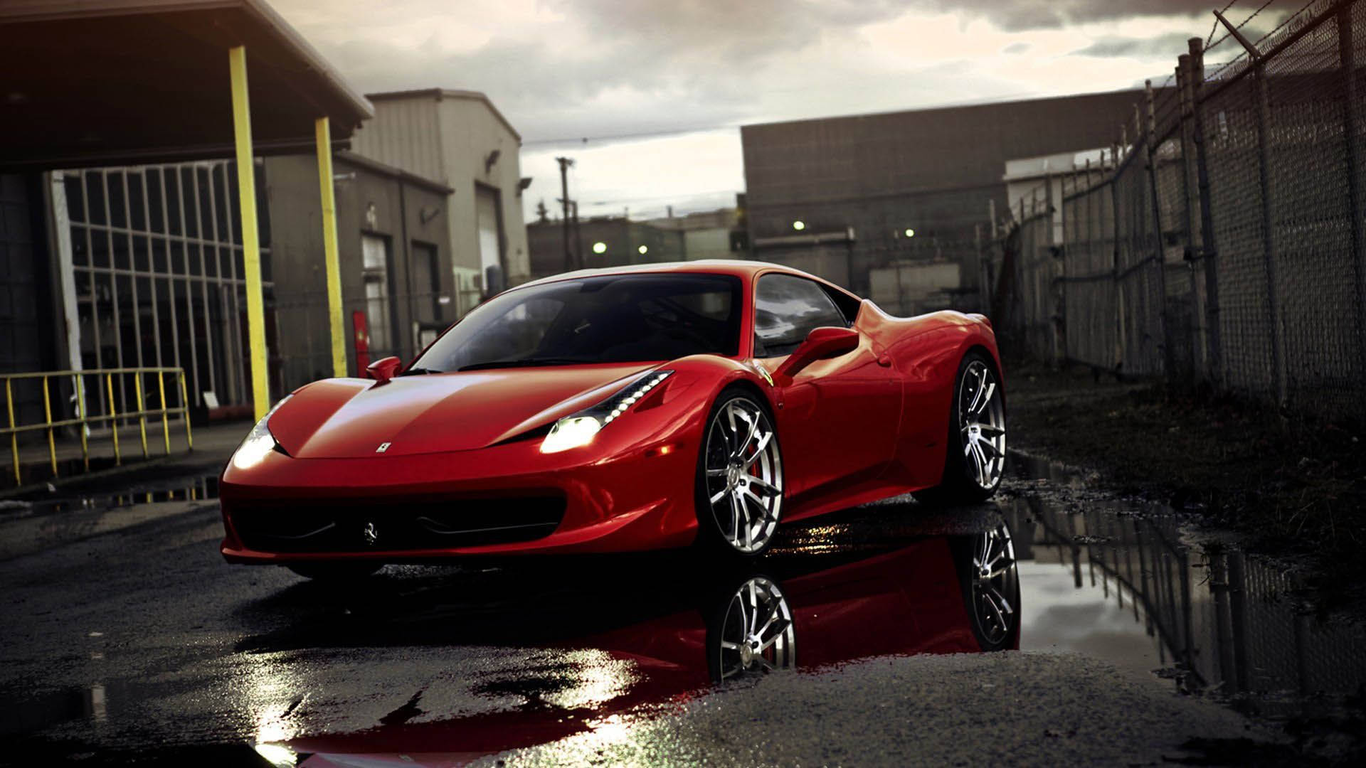 1920x1080 Ferrari 458 Rosso Corsa 壁紙 — 一輛光亮的紅色法拉利跑車在工業背景和陰天下，在雨水中閃閃發光。