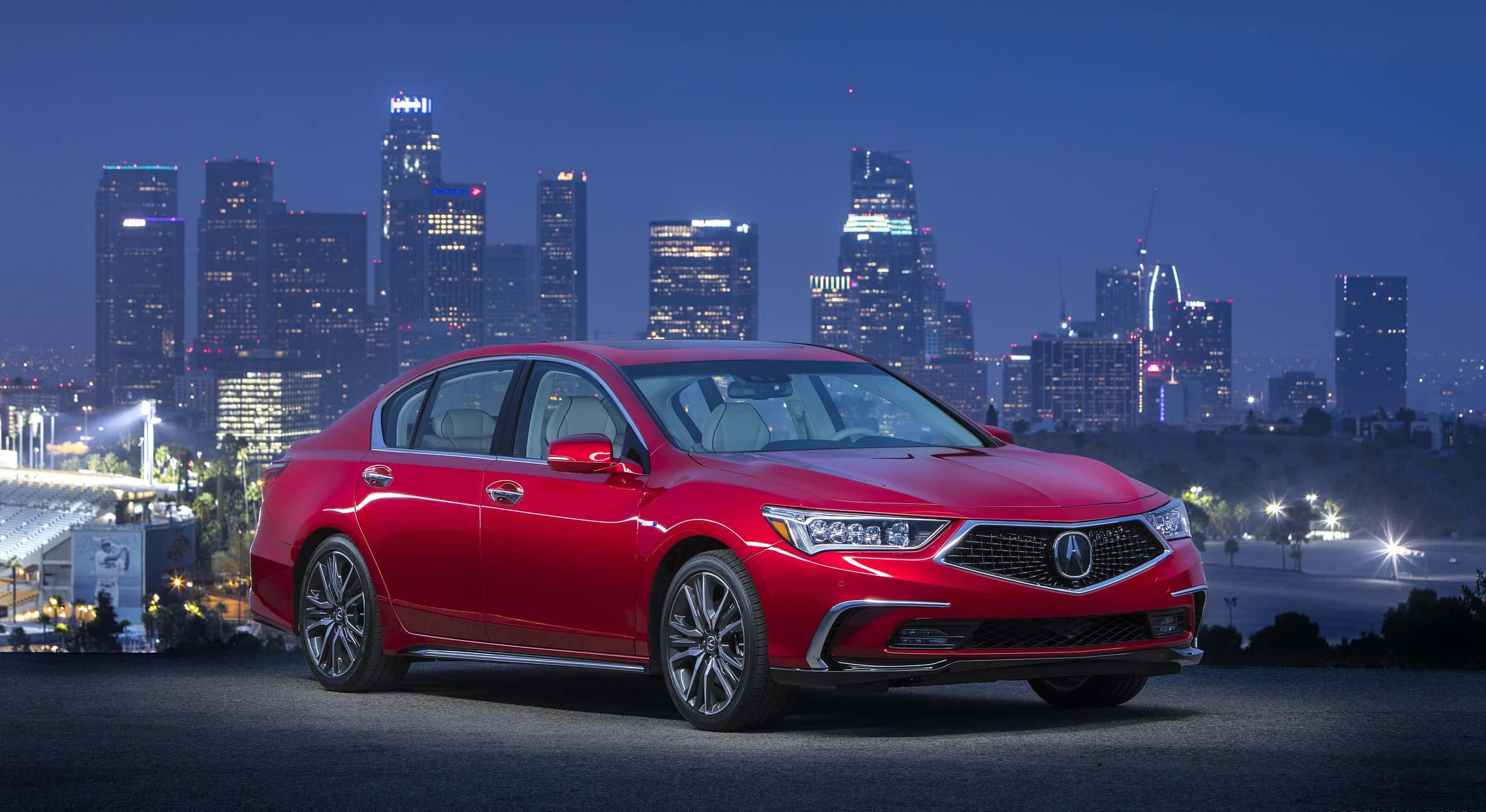 Acura Rlx 桌布 壁紙 — 一輛光亮的紅色轎車停泊在山上，俯瞰黃昏時分充滿活力的城市天際線。