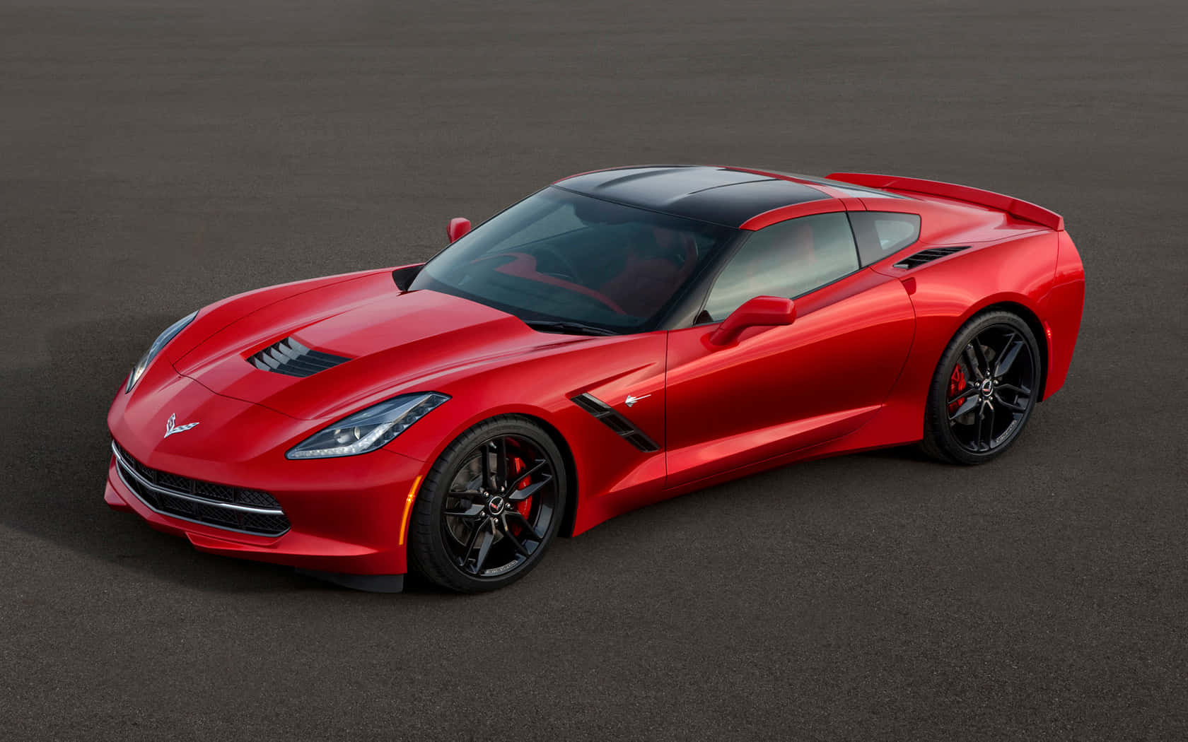 Chevrolet Corvette Stingray 桌布 壁紙 — 一輛光亮的紅色雪佛蘭Corvette跑車，帶有黑色飾件和紅色制動卡鉗，停在深灰色表面上。