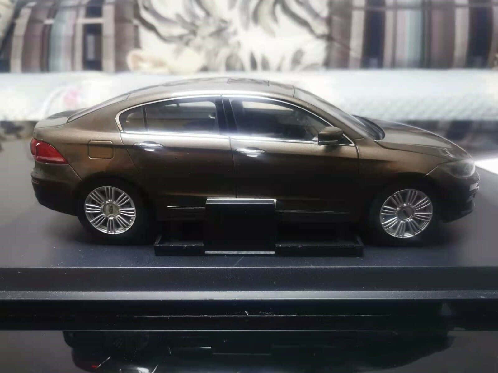 Qoros 桌布 壁紙 — 一輛光滑的青銅色轎車模型車，展示在黑色底座上，背景是模糊的虎紋圖案。