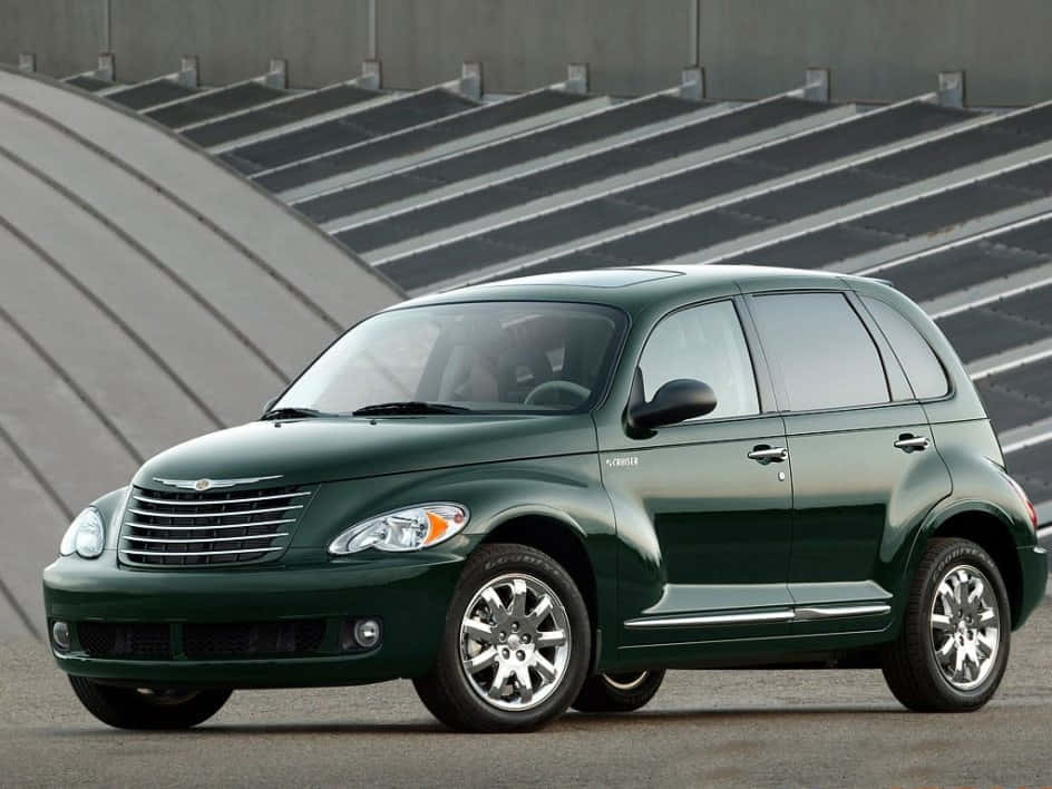Chrysler Pt Cruiser 桌布 壁紙 — 一輛光澤深綠色的克萊斯勒 PT Cruiser 停放在一個現代混凝土體育場前，設有分層座位。