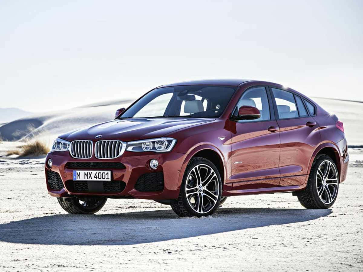 Bmw X4 桌布 壁紙 — 一輛光澤的栗色BMW X4 SUV停放在陽光明媚的沙漠中，背景是沙丘。