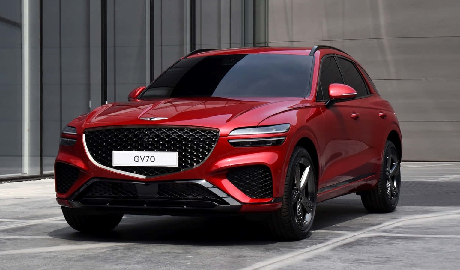 Genesis Gv70 桌布 壁紙 — 一輛光澤的紅色Genesis GV70 SUV停在一棟現代玻璃和混凝土建築前。