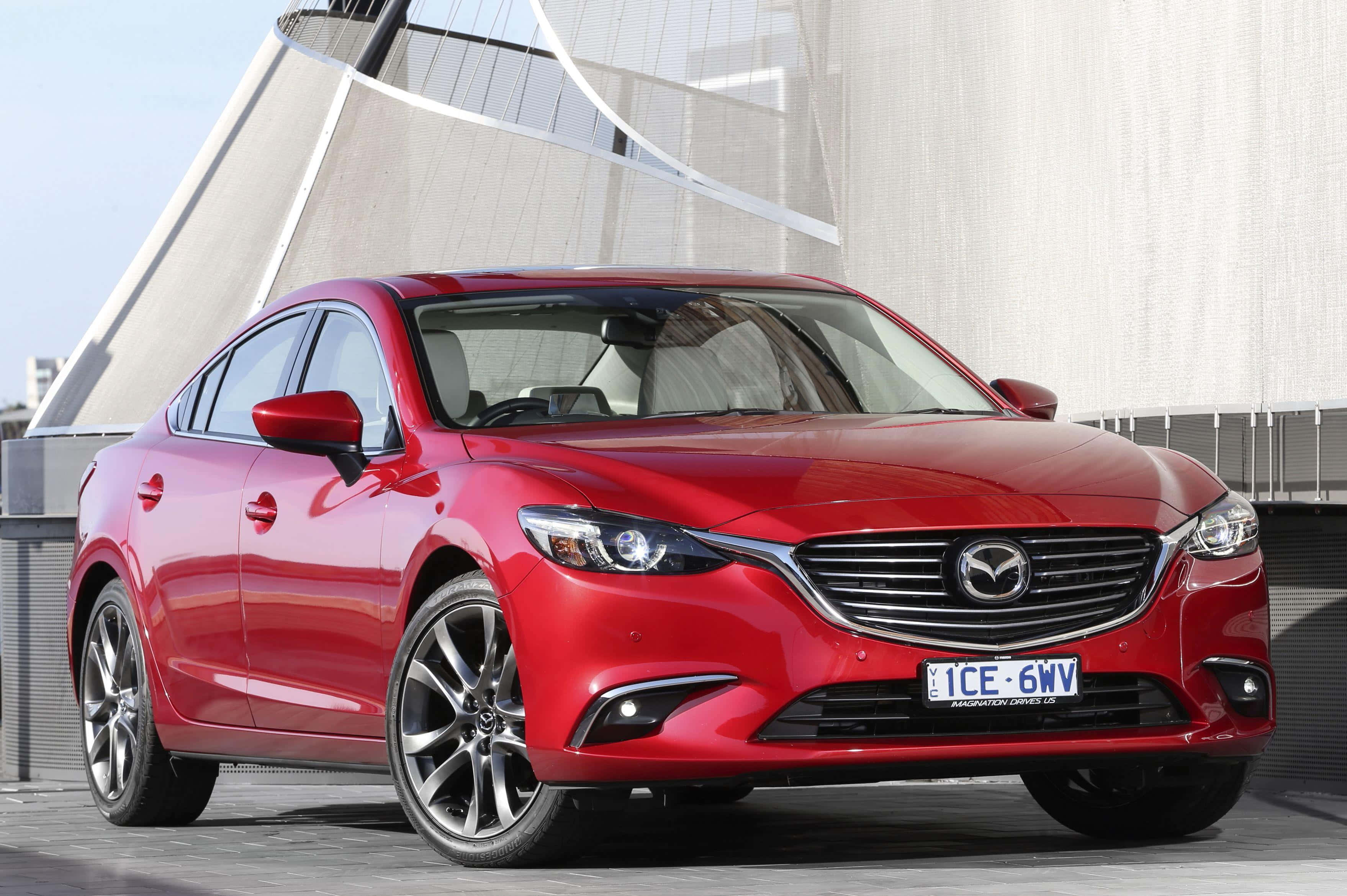 Mazda 6 桌布 壁紙 — 一輛光澤的紅色Mazda6轎車停放在現代化的屋頂上，背後有彎曲的建築結構。