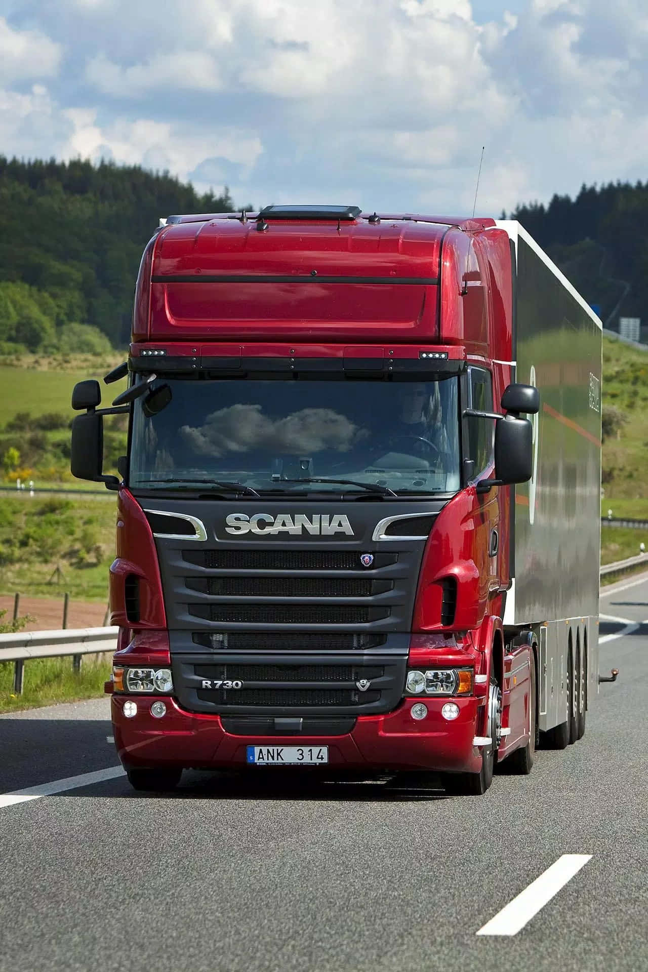 貨車 桌布 壁紙 — 一輛光澤的紅色Scania R730卡車拖著銀色拖車，在部分多雲的天空下，行駛在兩旁綠丘環繞的陽光高速公路。