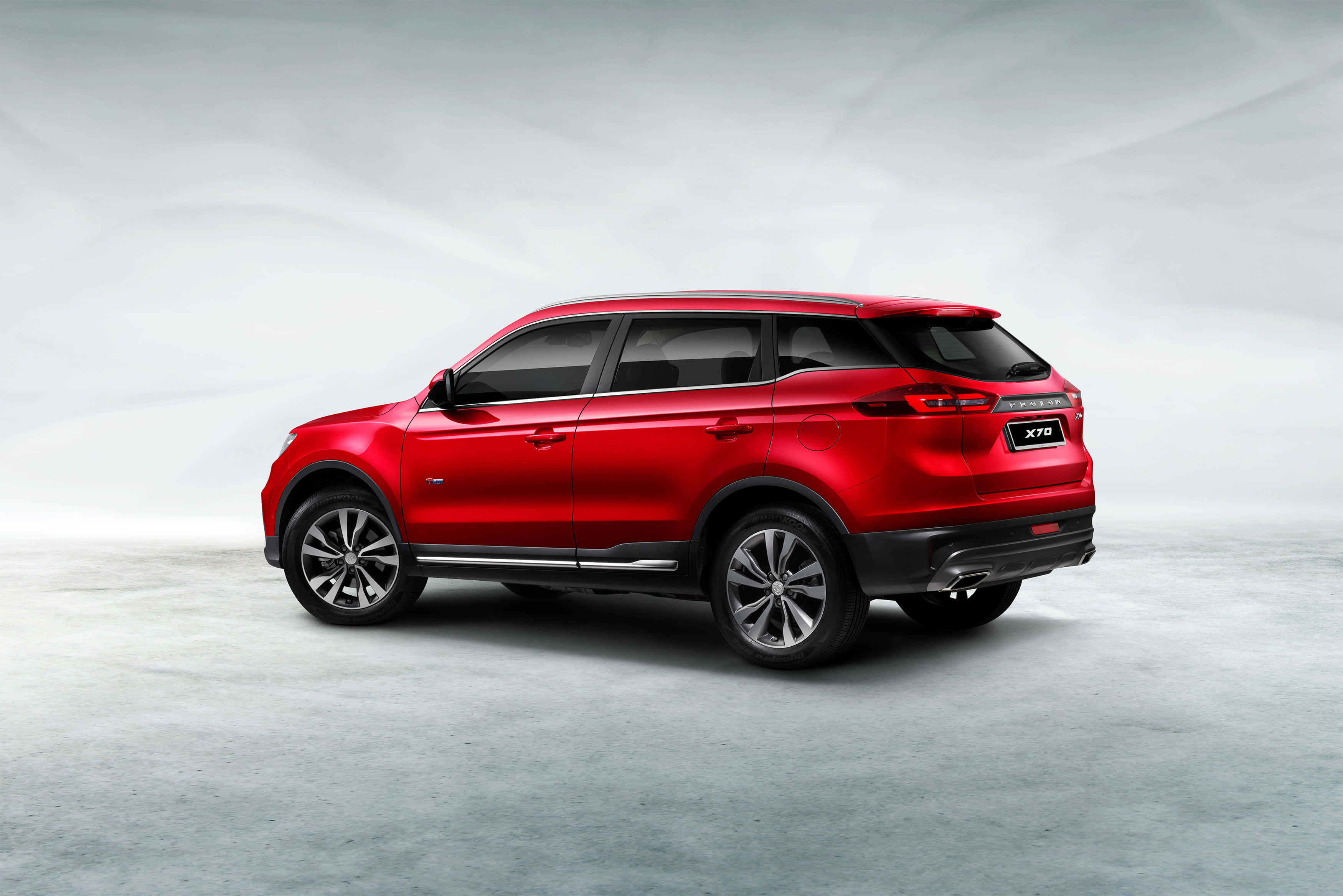 Proton 桌布 壁紙 — 一輛光澤的紅色SUV，擁有流暢曲線和銀色輪圈，在極簡灰色工作室背景前矗立。