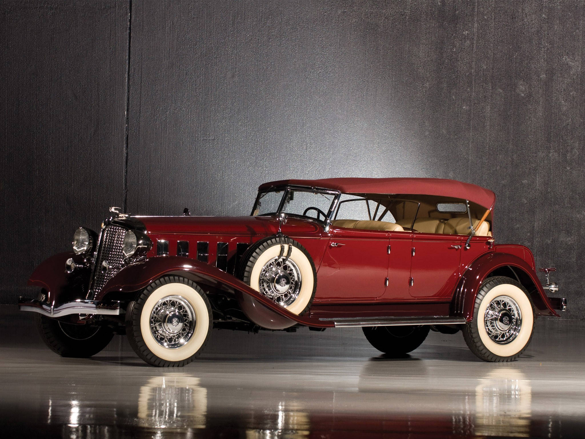 Chrysler Imperial Parade Phaeton 壁紙 — 一輛光澤的紅色復古敞篷車，配備白色輪胎，在攝影棚燈光下於深色紋理背景中閃耀。