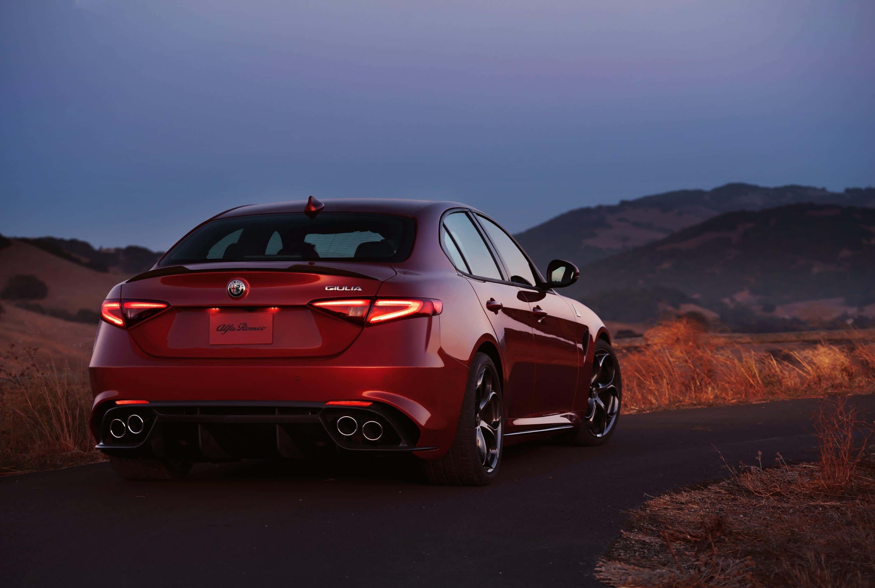 Alfa Romeo Giulia 桌布 壁紙 — 一輛光澤的紅色愛快羅密歐Giulia房車在黃昏時分在蜿蜒的道路上閃耀，背景是山丘。