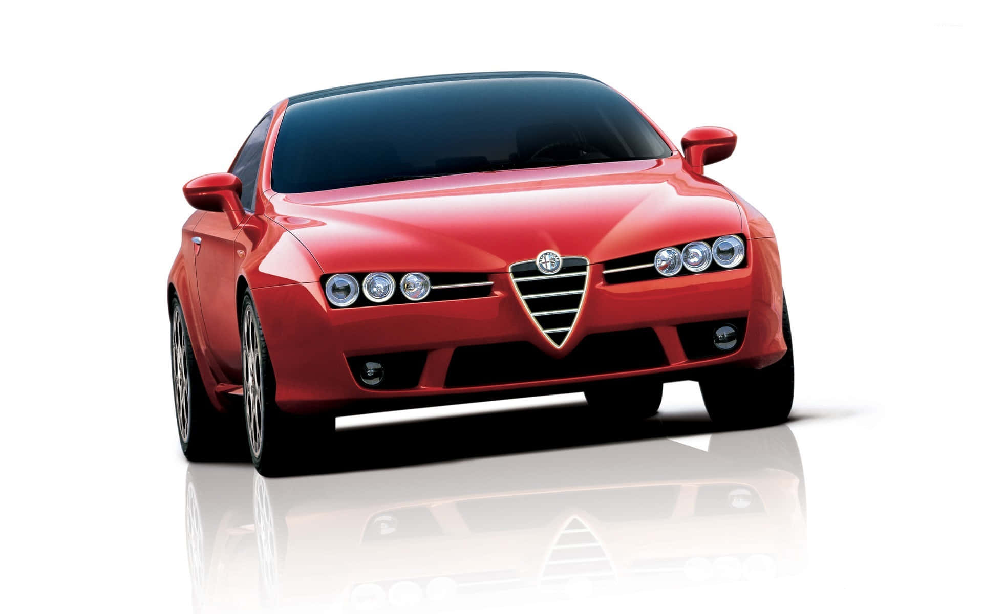 Alfa Romeo Brera 桌布 壁紙 — 一輛光澤的紅色愛快羅密歐跑車，配備四頭燈和標誌性鬼面罩，佇立在反光的白色工作室地板上。