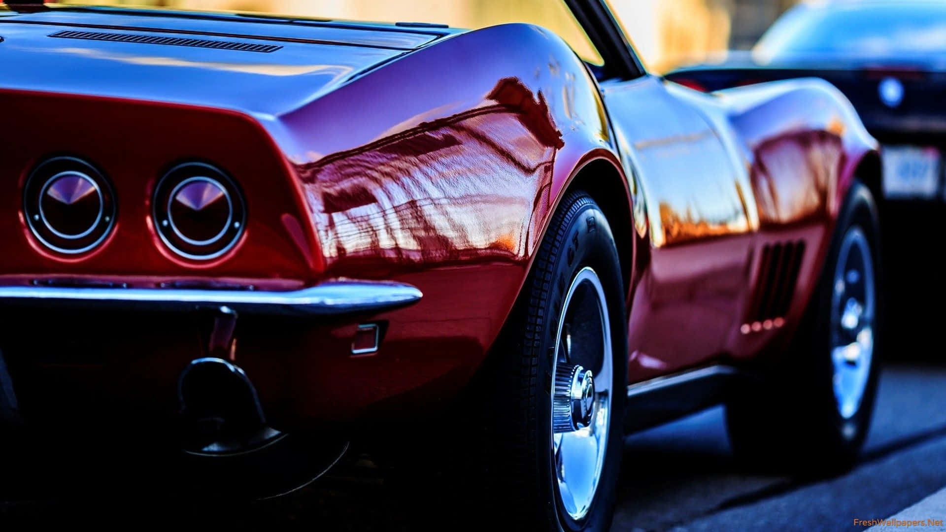 classic 桌布 壁紙 — 一輛光澤的紅色經典肌肉車在其彎曲的車身面板上反射出溫暖的日落天空。