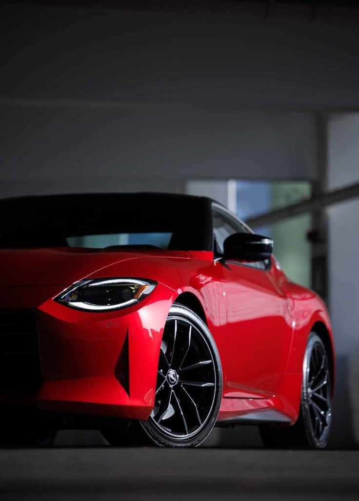 Sports Car 桌布 壁紙 — 一輛光澤的紅色跑車配黑色輪圈，停放在光線昏暗、帶柔和環境照明的車庫中。