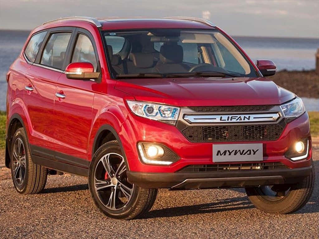 Lifan 桌布 壁紙 — 一輛光澤紅色力帆Myway SUV在黃金時段停在水邊碎石上，車頭燈亮著。