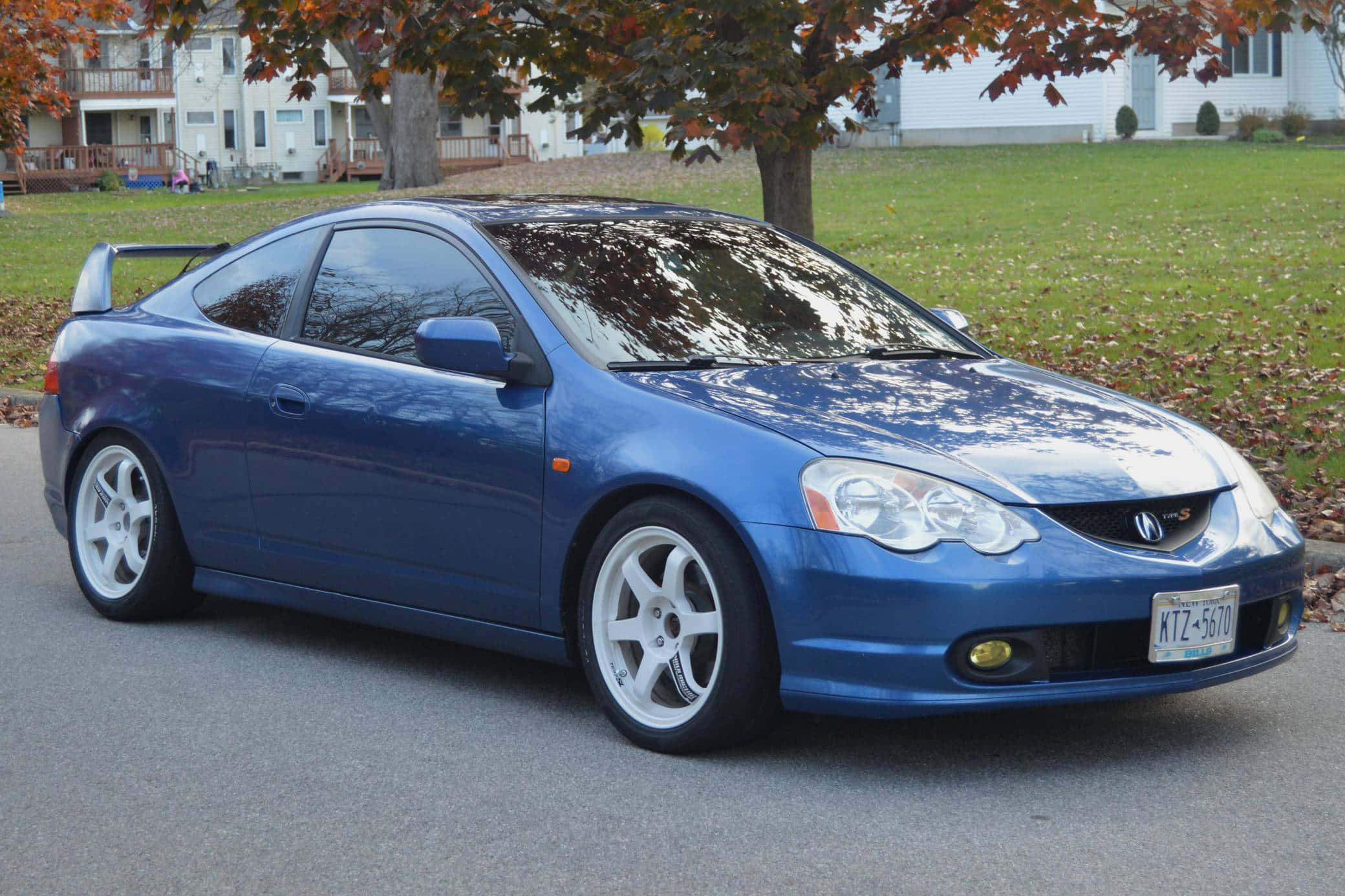 Acura Rsx 桌布 壁紙 — 一輛光澤藍色Acura RSX運動轎跑車停泊在郊區街道上，周圍是秋天的樹木和落葉。
