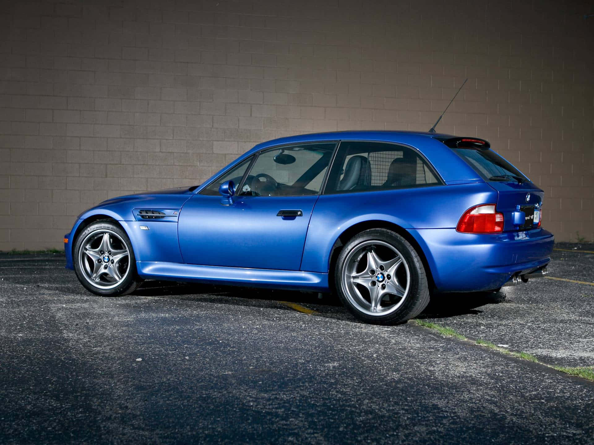 Bmw Z3 桌布 壁紙 — 一輛光澤藍色BMW M3旅行車在夜間停泊在混凝土牆旁，帶有戲劇性的燈光。