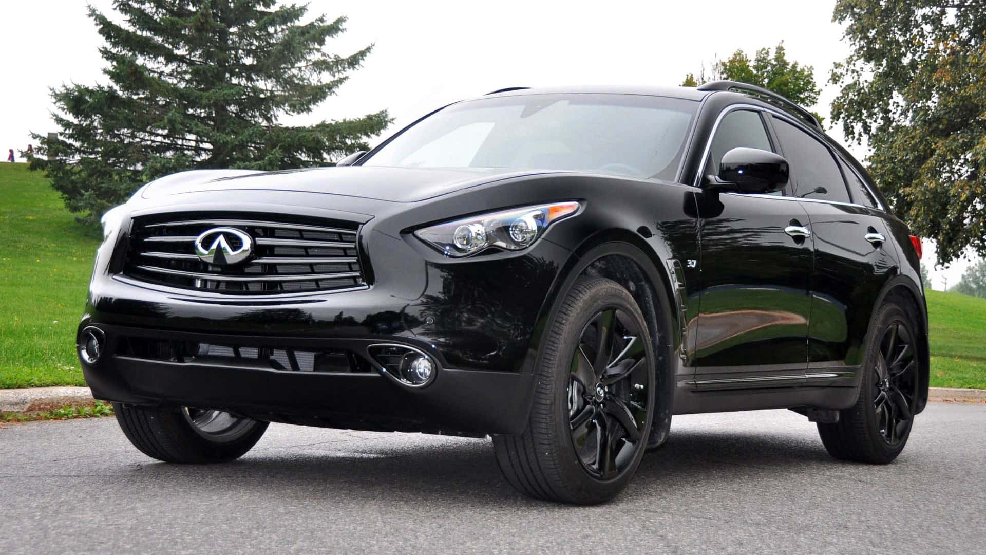 Infiniti Qx70 桌布 壁紙 — 一輛光澤黑色Infiniti FX35 SUV停泊在瀝青路上，背景有綠草和樹木。